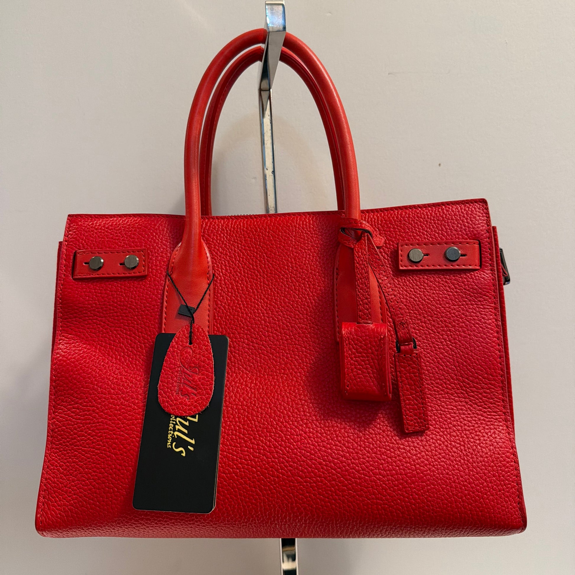 Red leather handbag with a tag on a light beige background