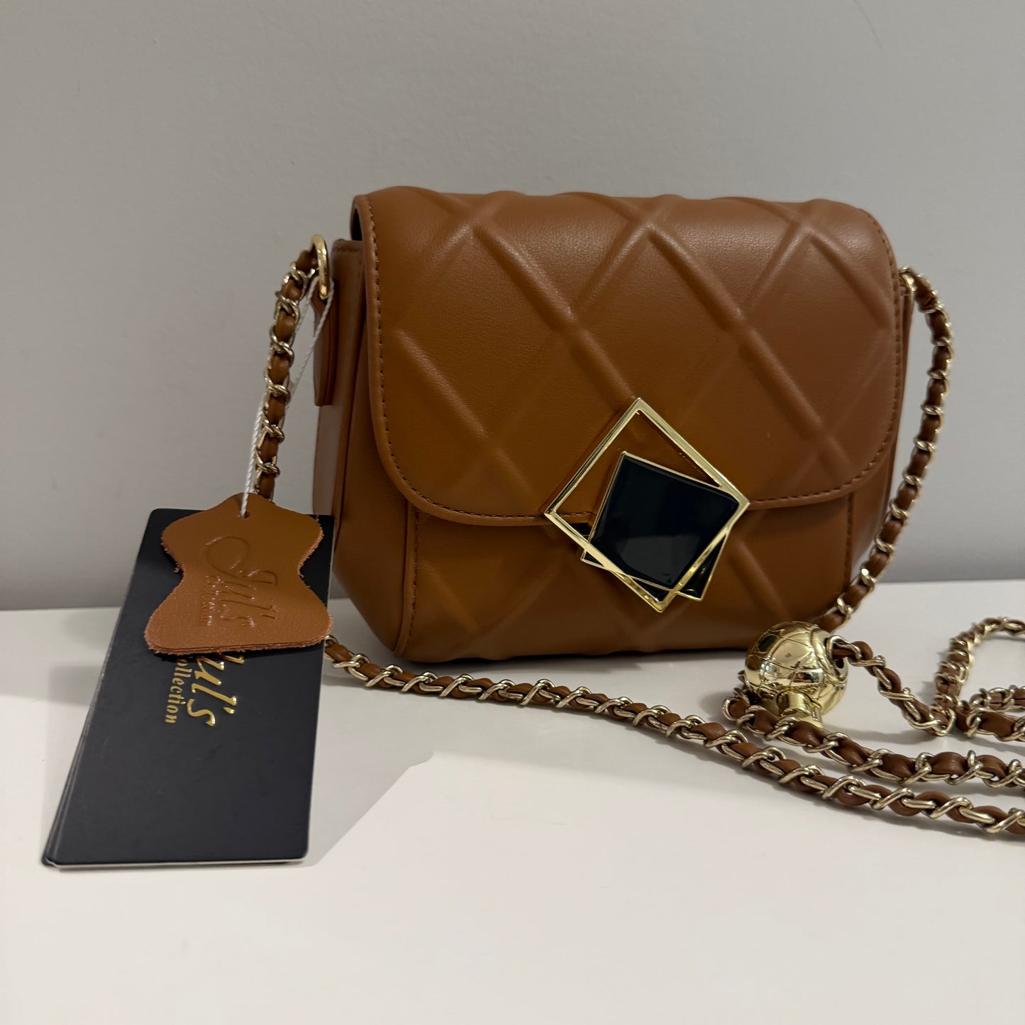 Brown quilted handbag with gold chain strap on a white surface