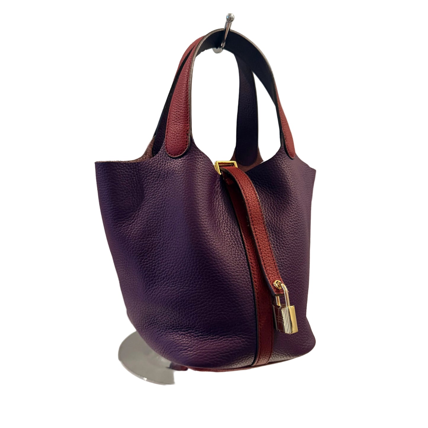 Purple leather handbag with a gold clasp on a white surface against a gray background