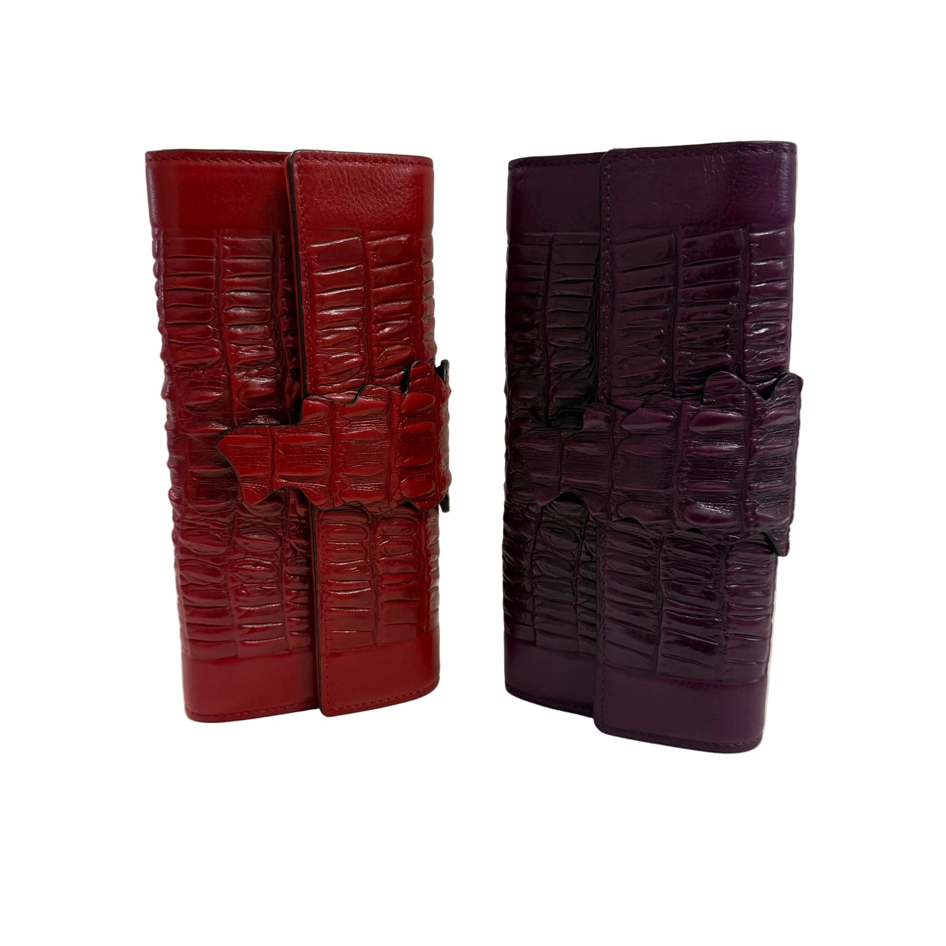 Two leather wallets, one red and one purple, on a light surface with a neutral background.