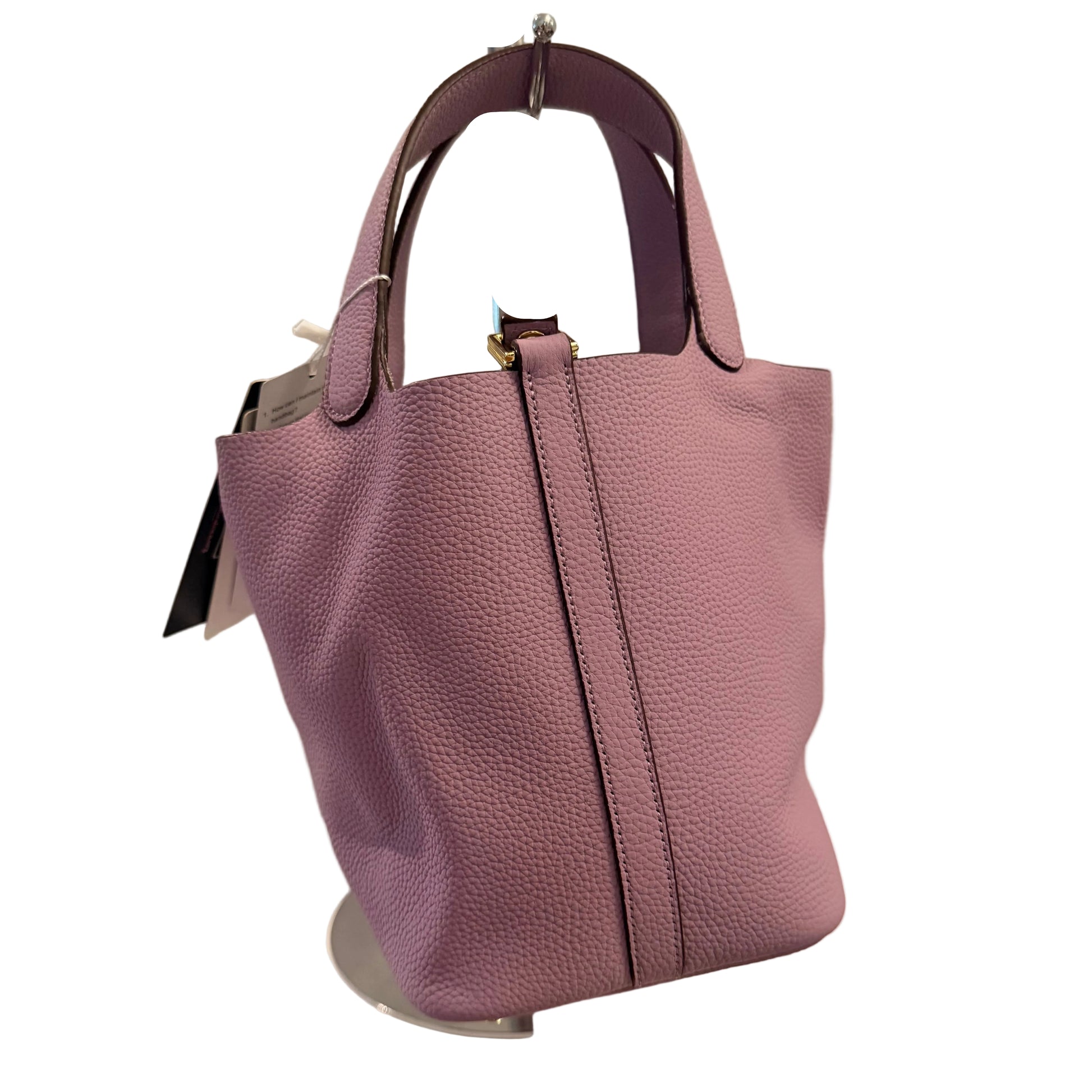Purple handbag on a stand with a neutral background