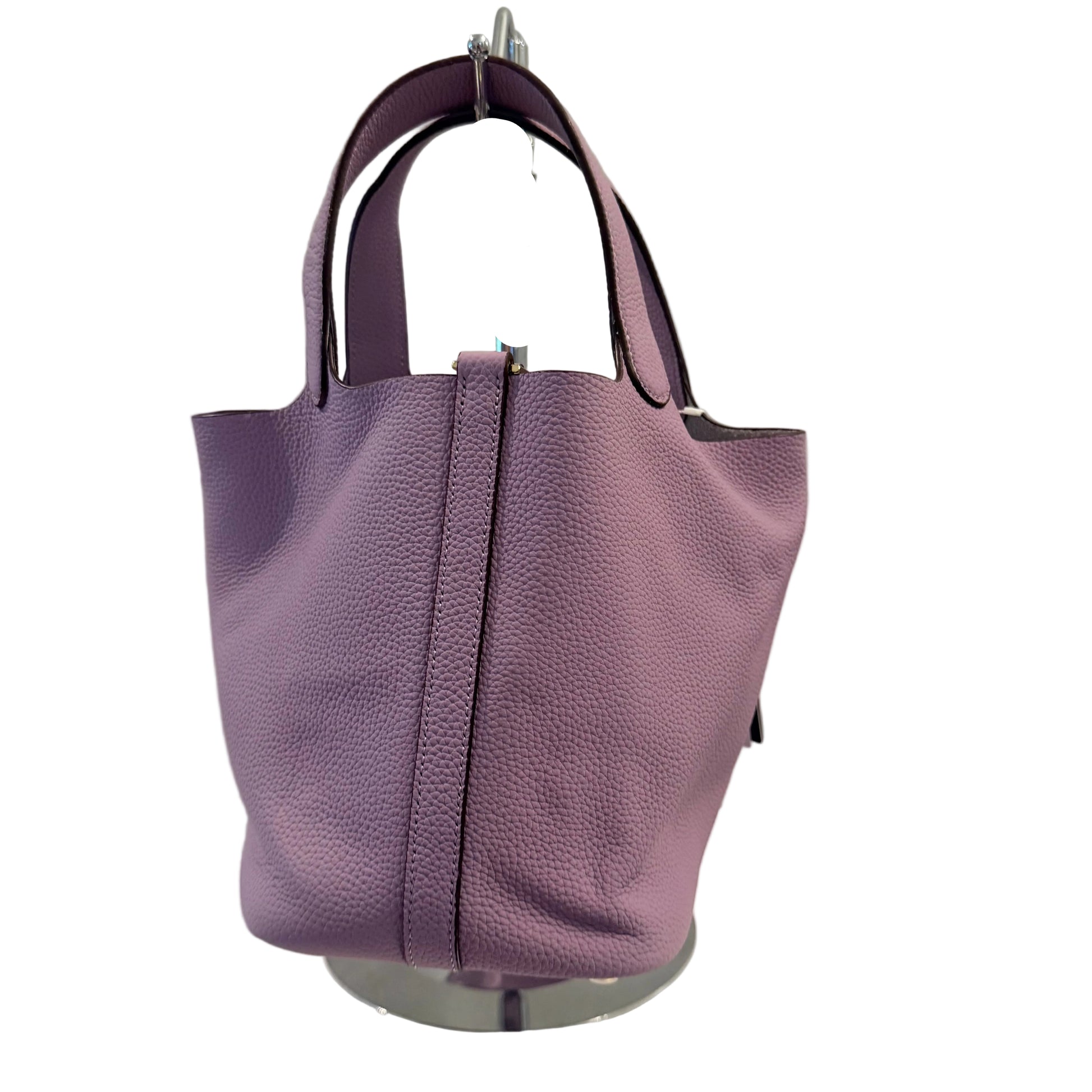 Purple handbag on a white surface with a gray background
