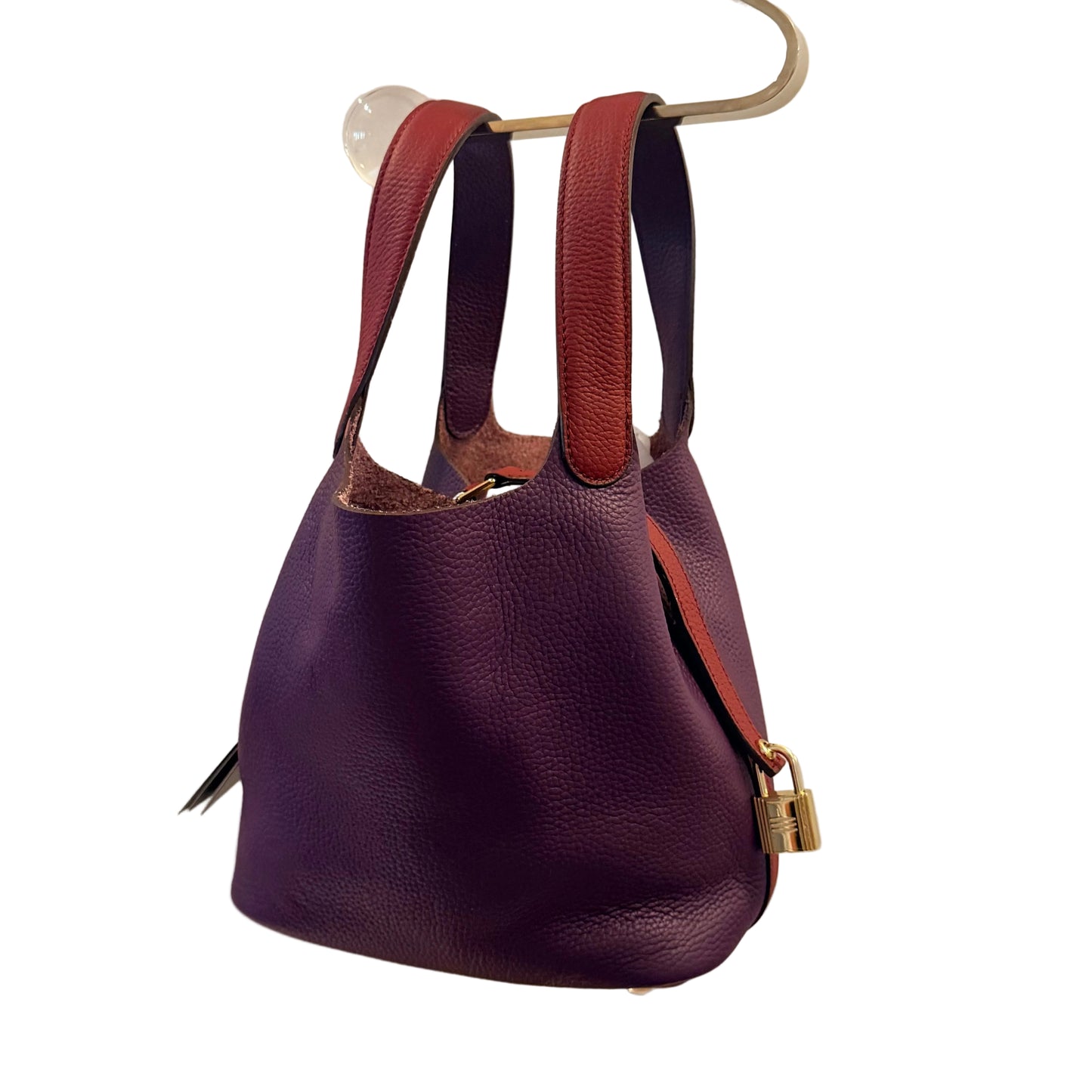 Purple leather handbag with brown straps on a beige background
