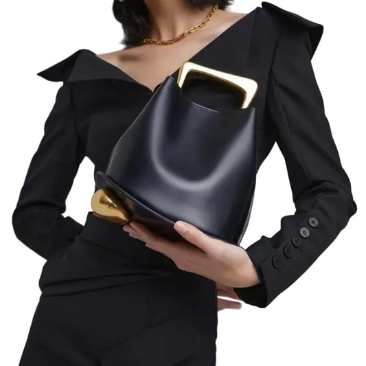 Person holding a black handbag with gold accents against a white background