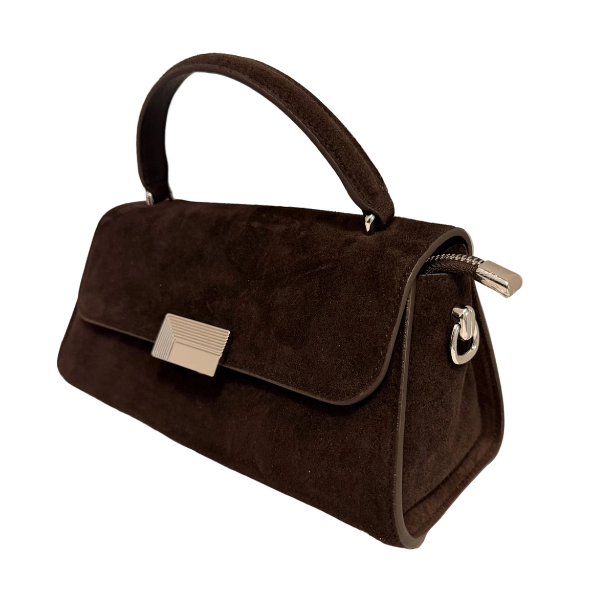 A dark brown suede handbag with a top handle, silver-tone hardware, and a zippered closure, resting on a white surface against a light gray wall.