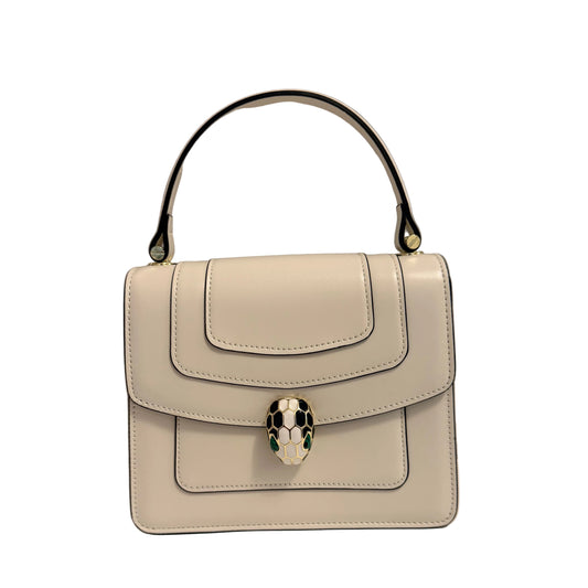 A structured top-handle handbag in off-white leather with a silver snake-head clasp and a black handle, set against a neutral gray background.