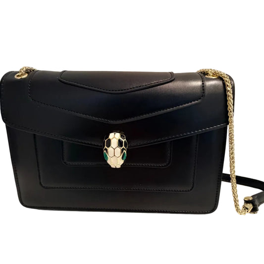 A black leather shoulder bag with a gold chain strap and a distinctive snake-head clasp, photographed on a light gray background.