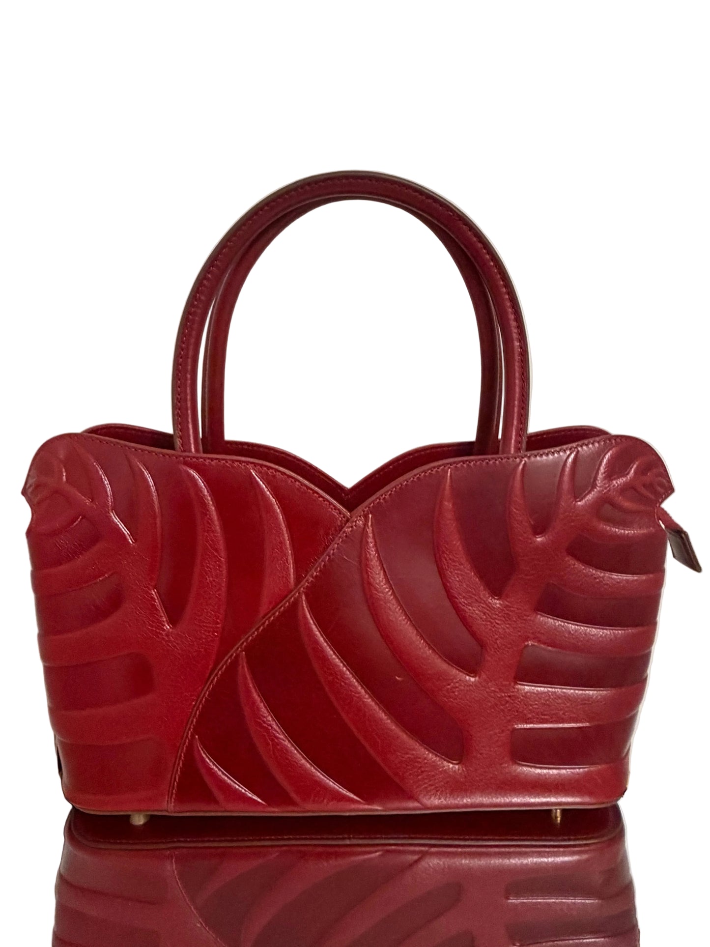 Red handbag with leaf-like design on a white background
