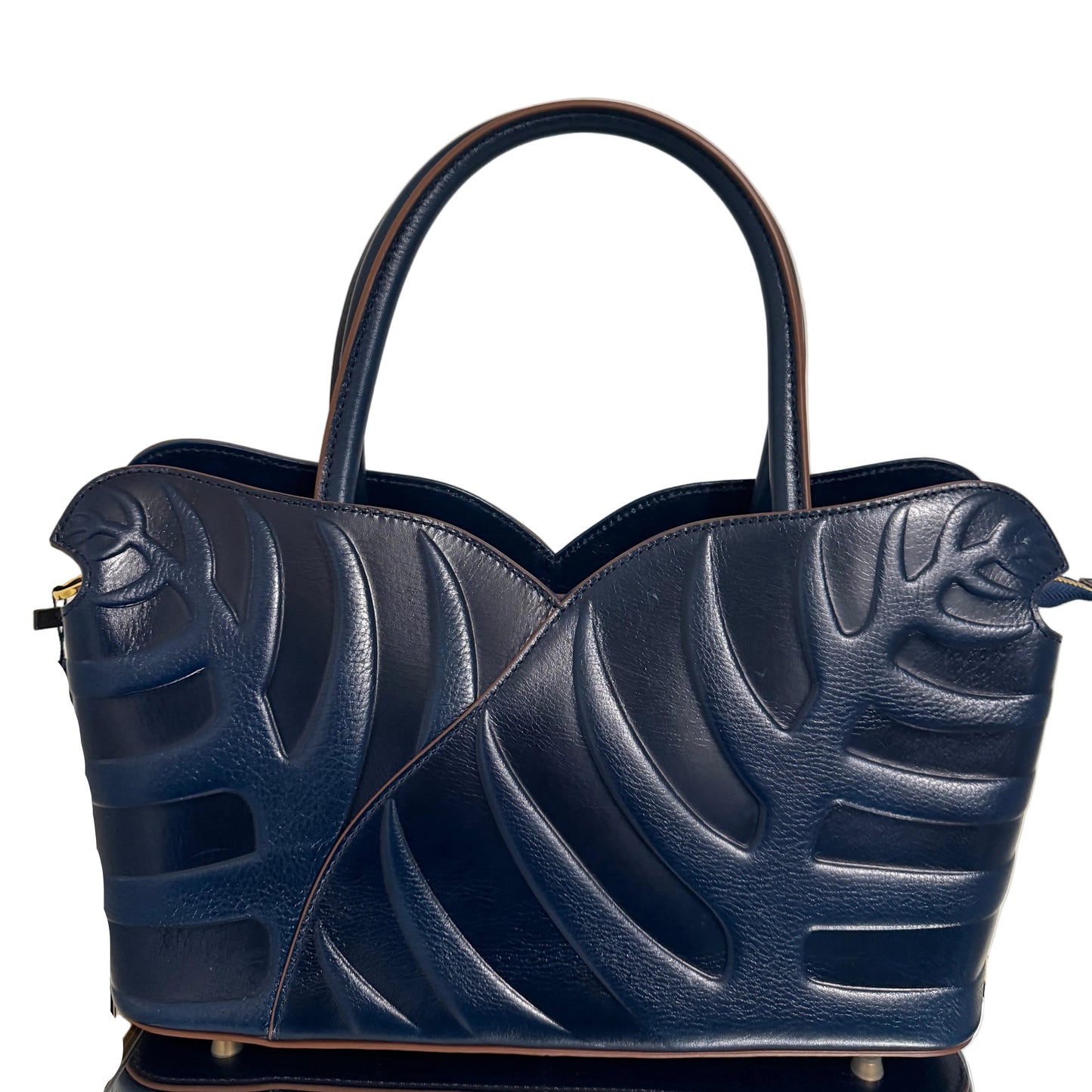Navy blue handbag with leaf-like design on a light gray background