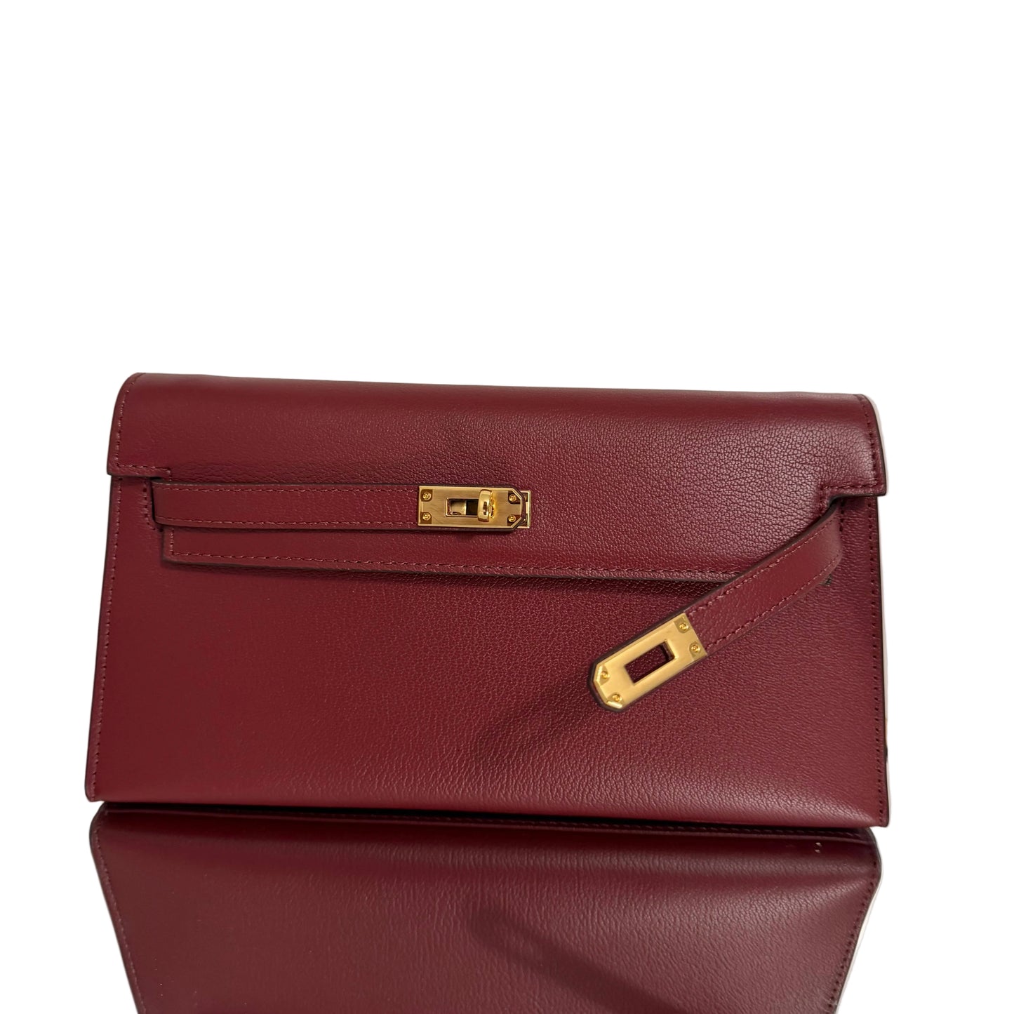 Maroon handbag with gold hardware on a light background