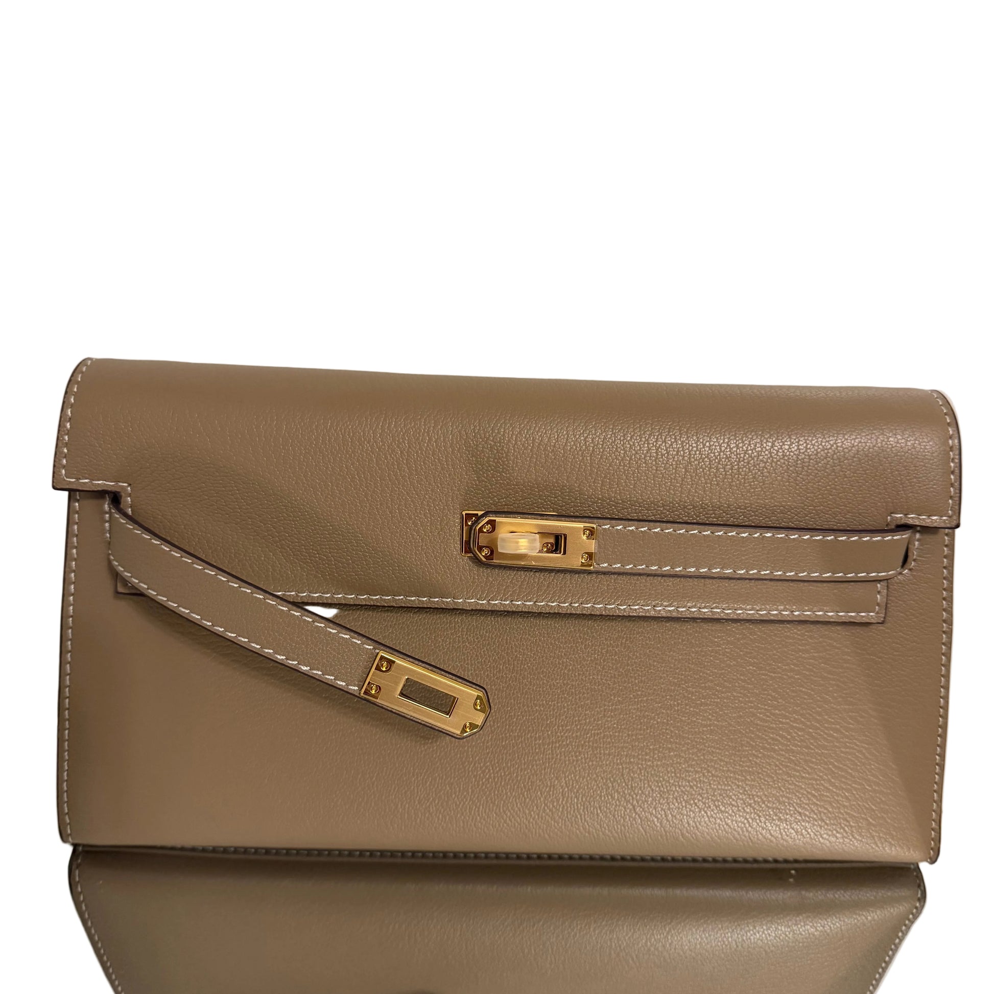 Brown leather handbag with gold accents on a light beige background