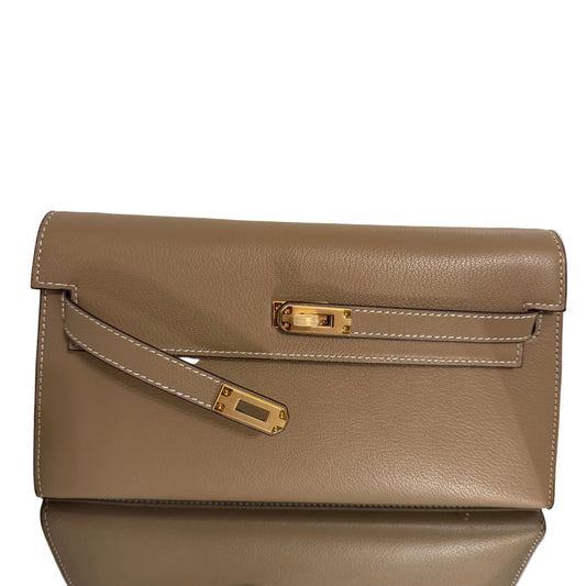 Brown leather handbag with gold accents on a light beige background