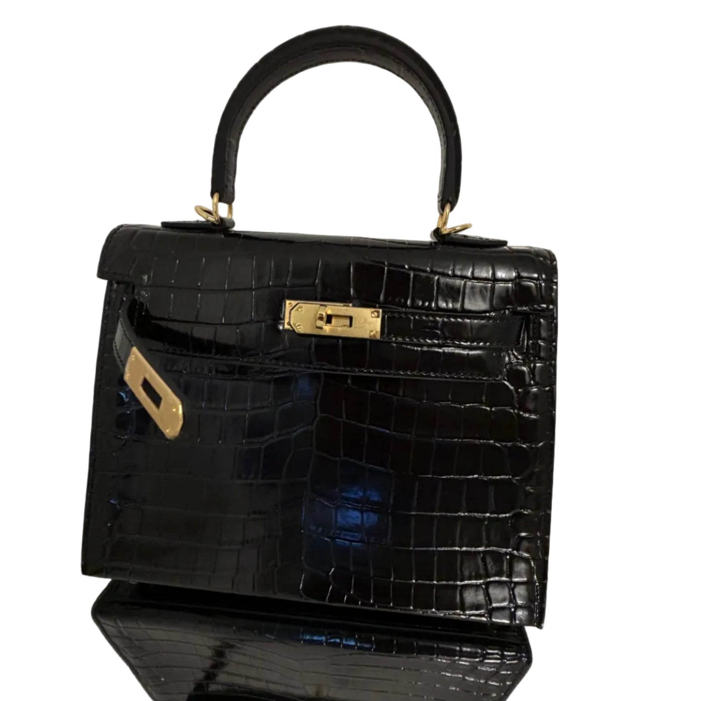 Black crocodile-patterned handbag with gold hardware on a reflective surface