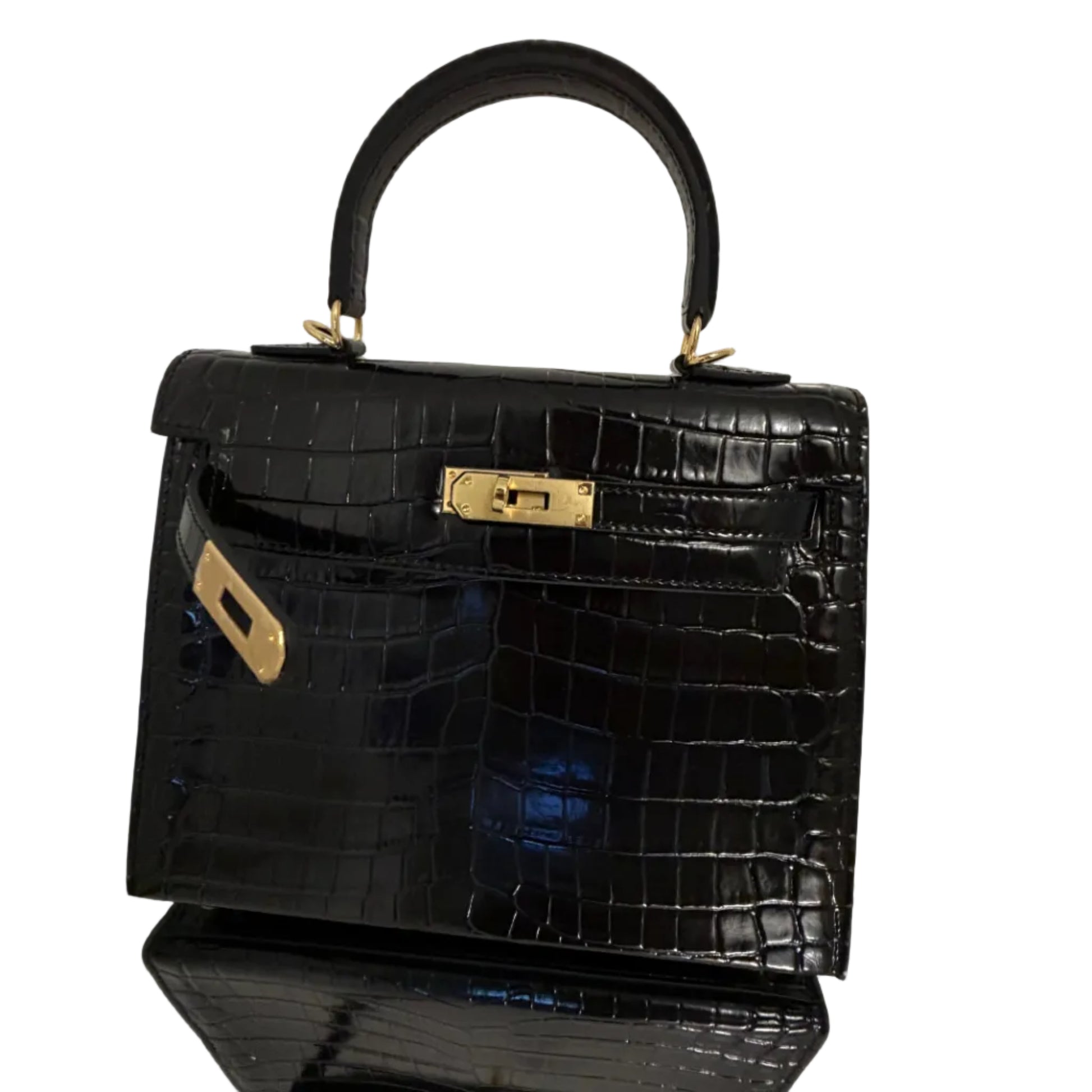 Black crocodile-patterned handbag with gold hardware on a reflective surface