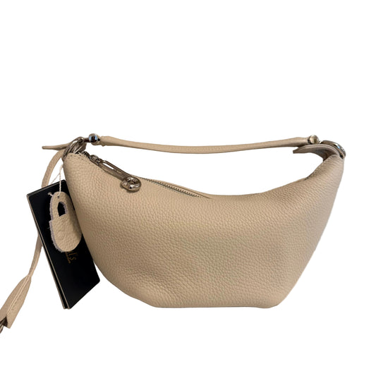 A cream-colored pebbled leather crescent-shaped shoulder bag with silver-tone hardware, shown with its black retail hangtag on a white surface against a light gray wall.