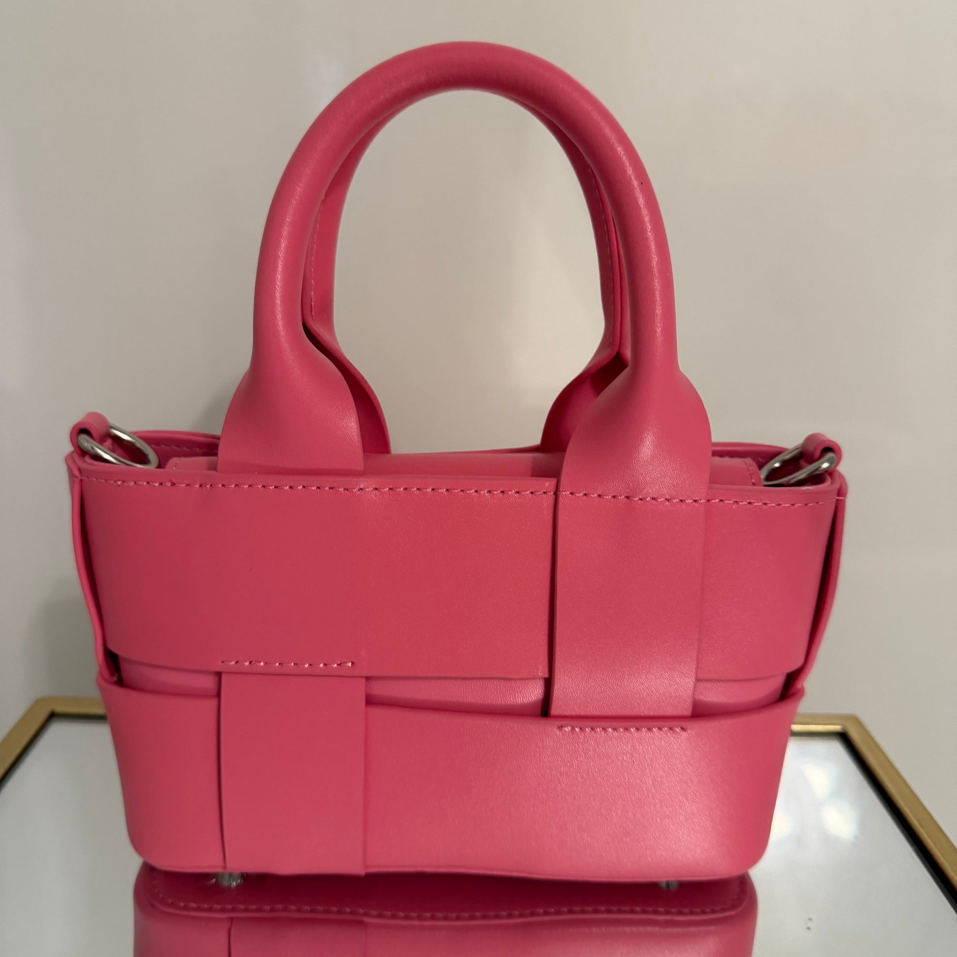 Pink handbag with woven detail on a light background