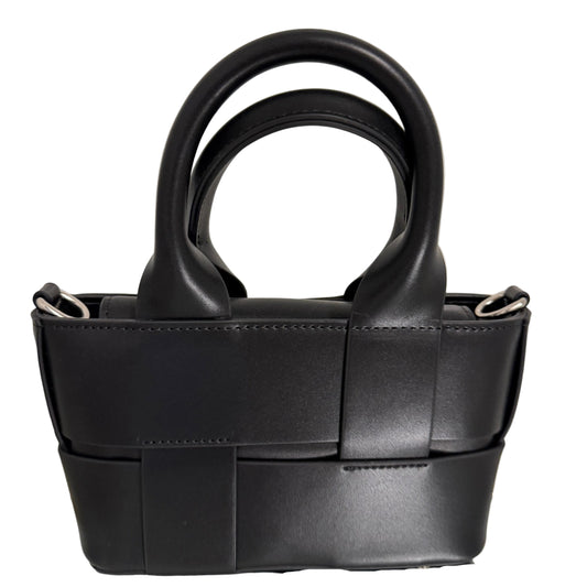 Black leather handbag with a unique design on a light beige background