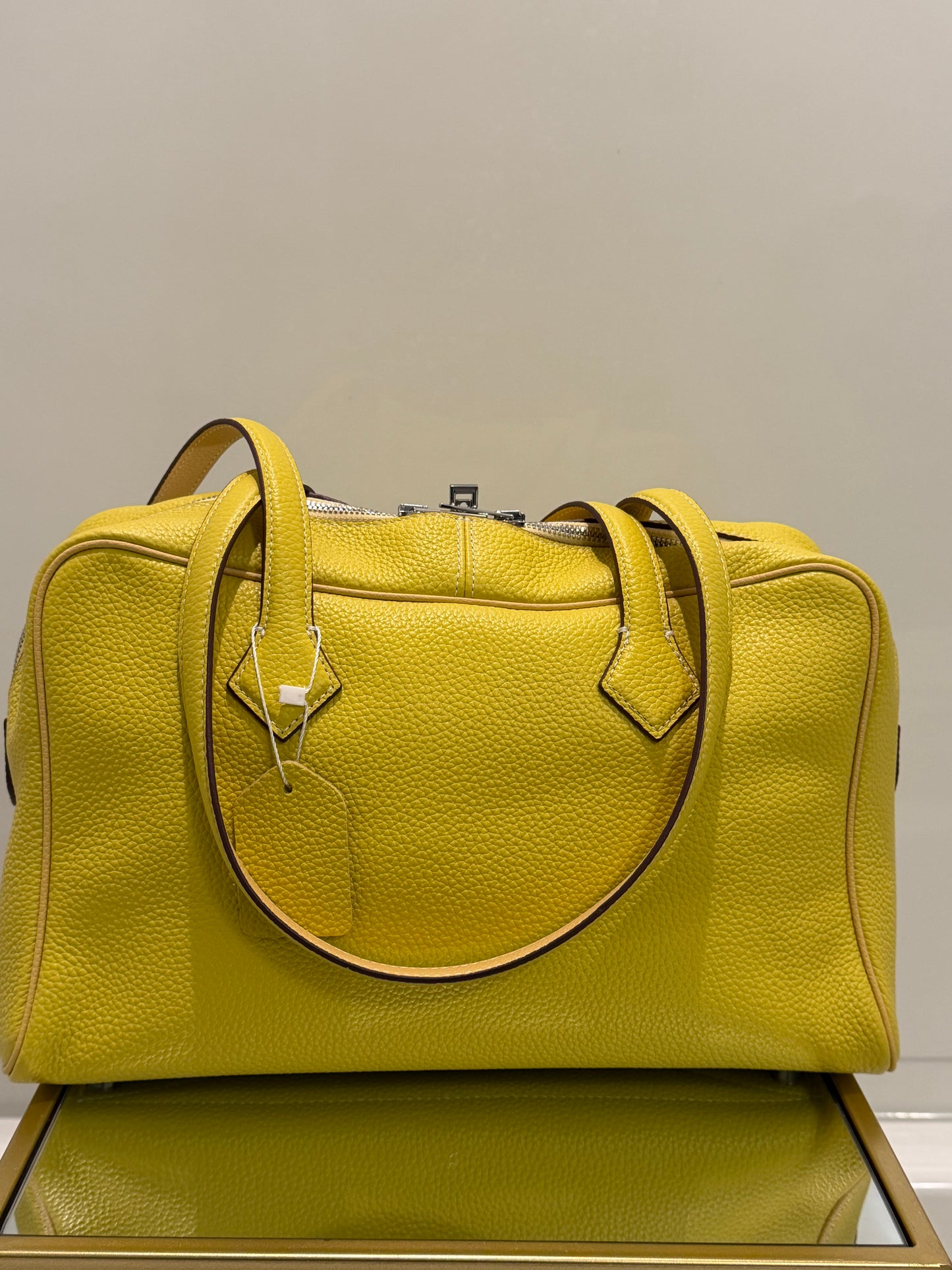 Green leather bag with a gold handle against a neutral background