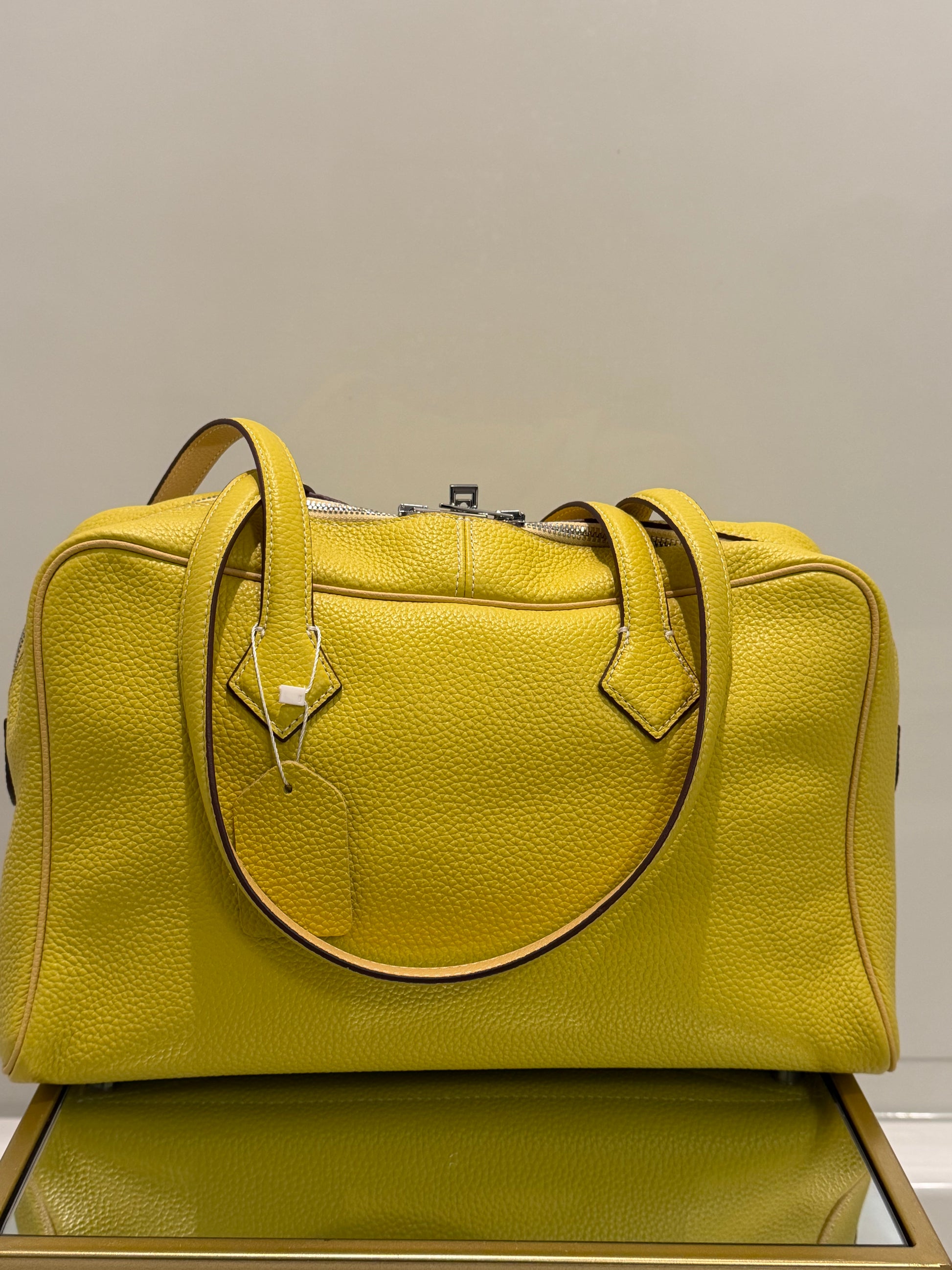 Green leather bag with a gold handle against a neutral background