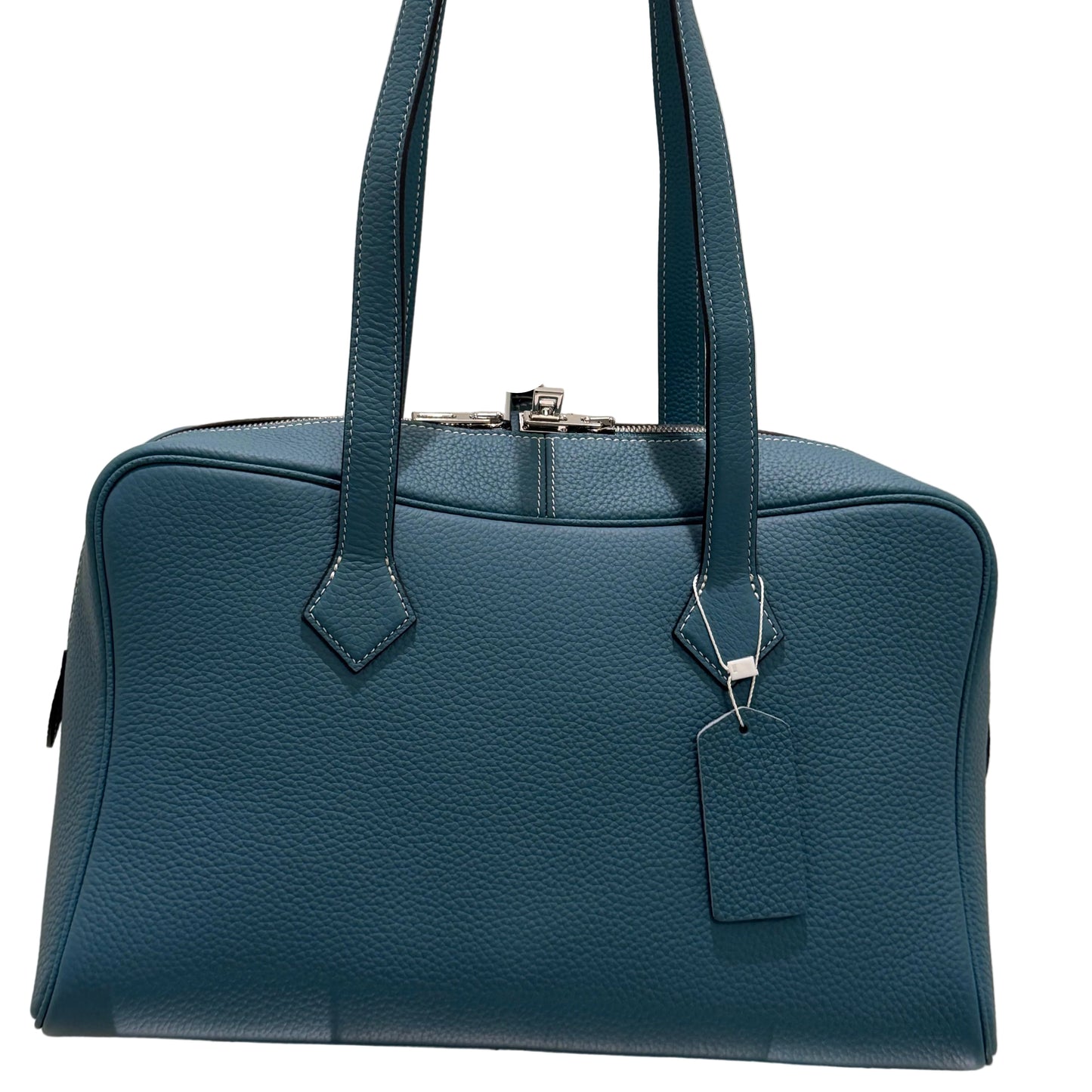 Blue leather handbag with a metallic clasp on a light beige background