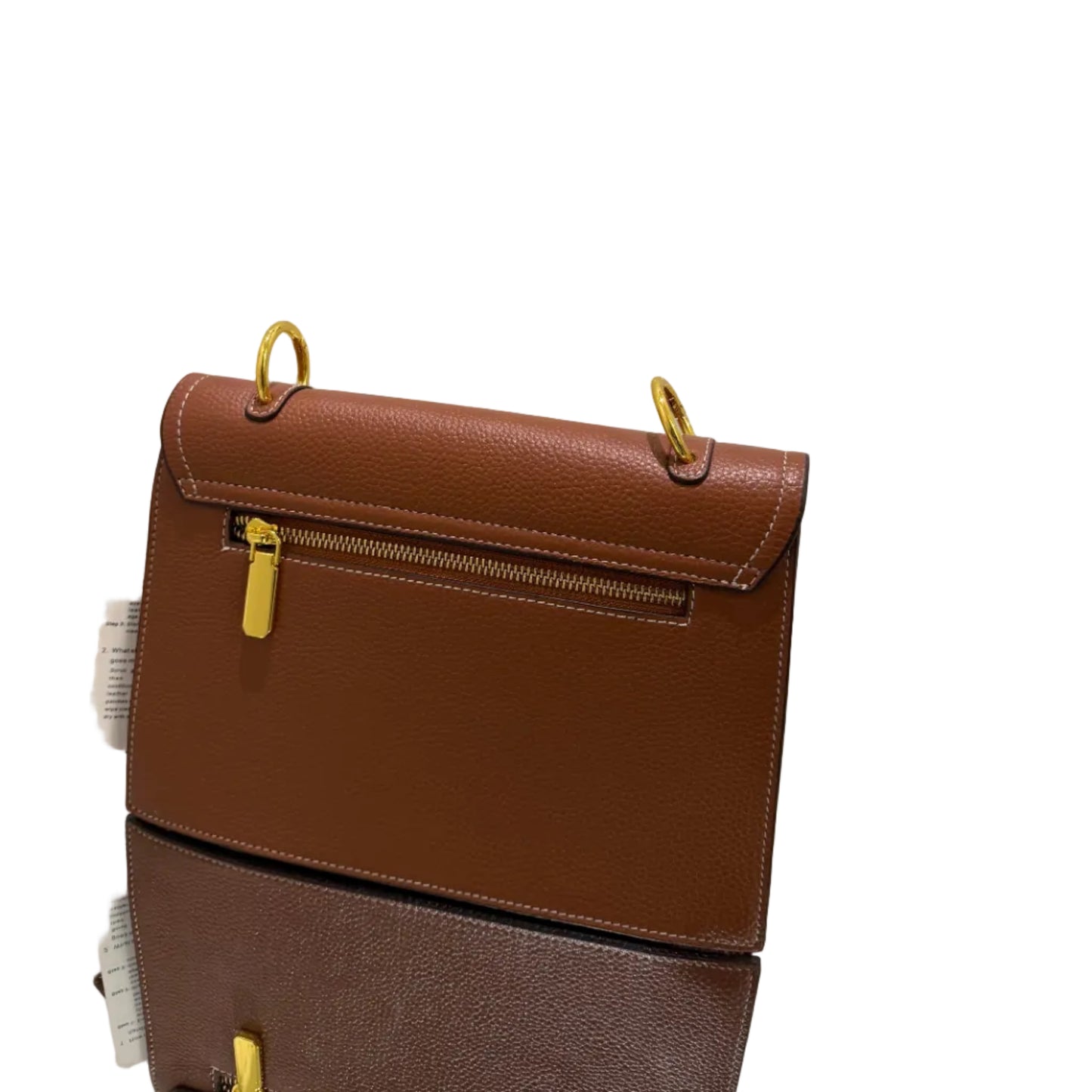 Brown leather handbag with gold hardware on a light gray background