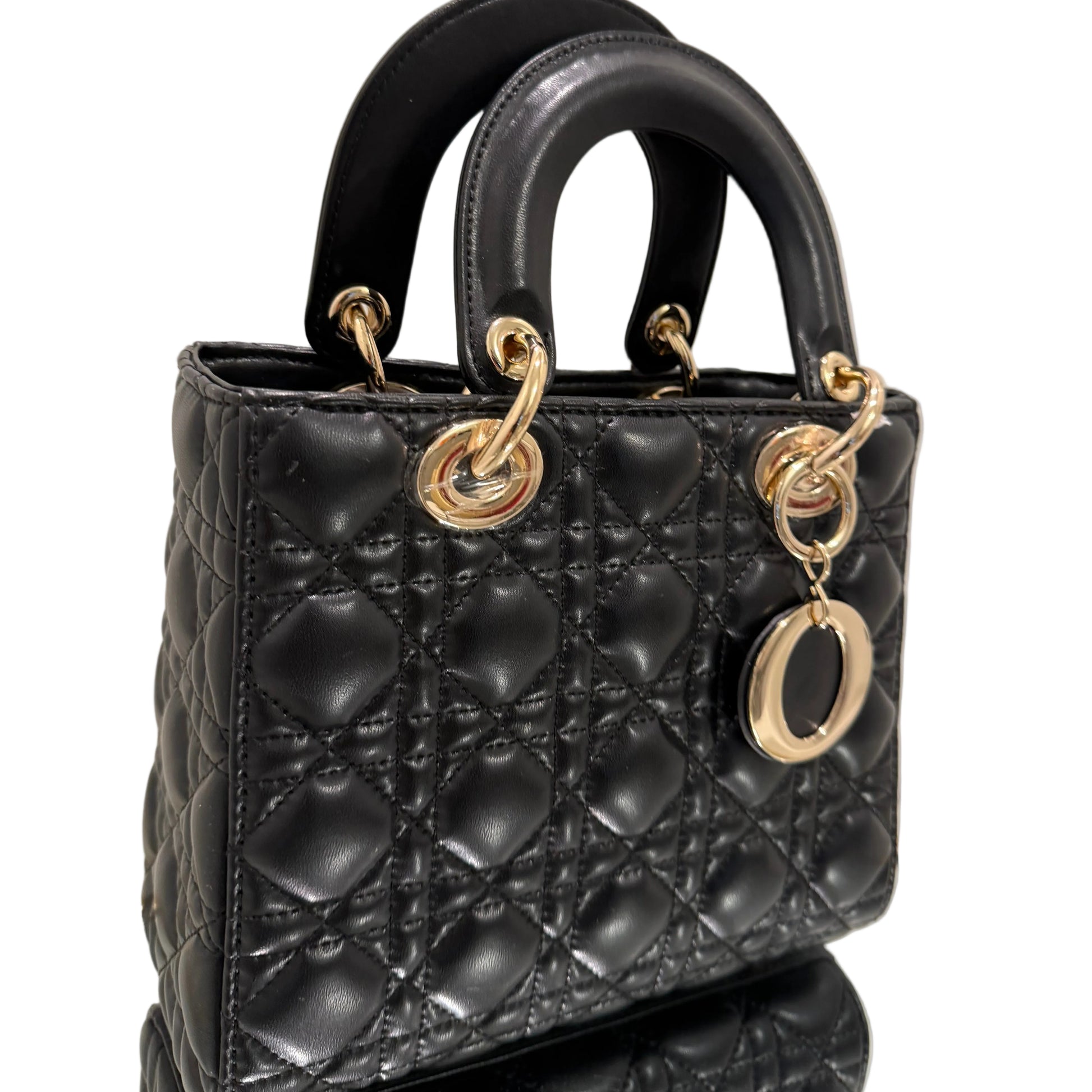 Black quilted handbag with gold hardware on a light background