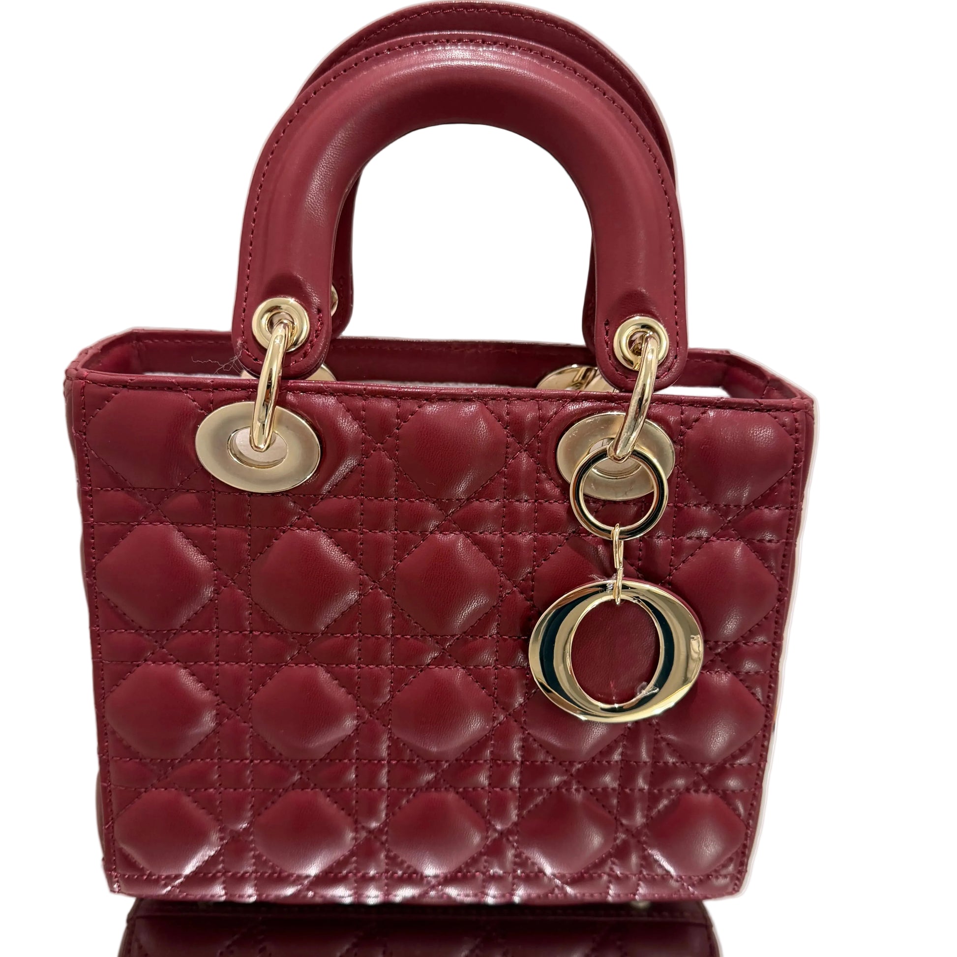 Maroon quilted handbag with gold hardware on a light beige background