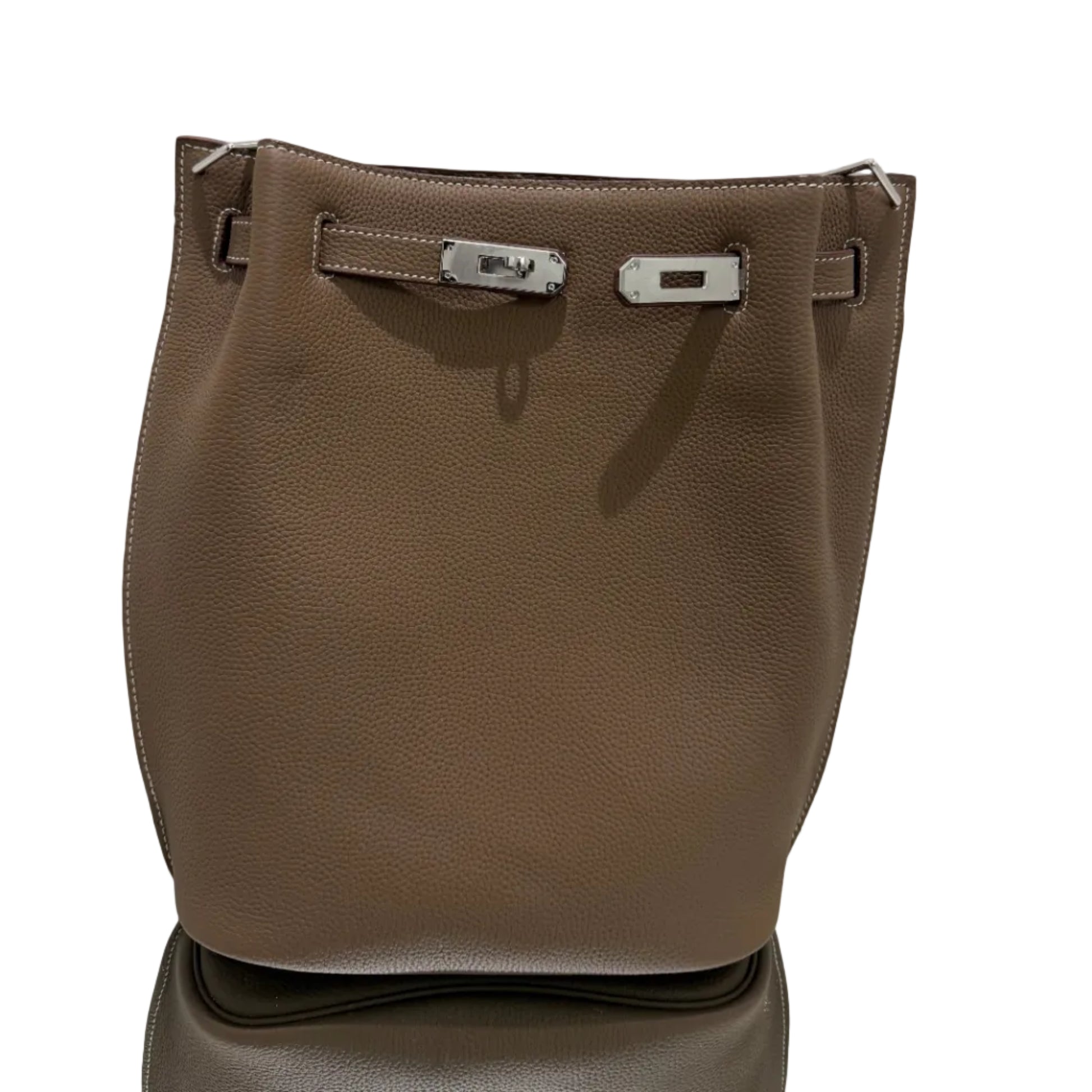 Brown leather bag with metal buckles on a light gray background