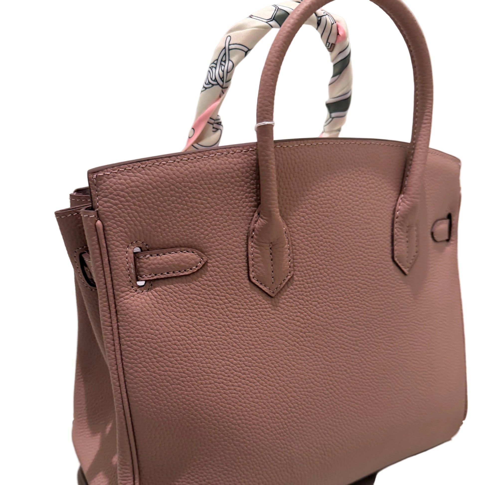 Brown leather handbag with floral patterned handle on a white background