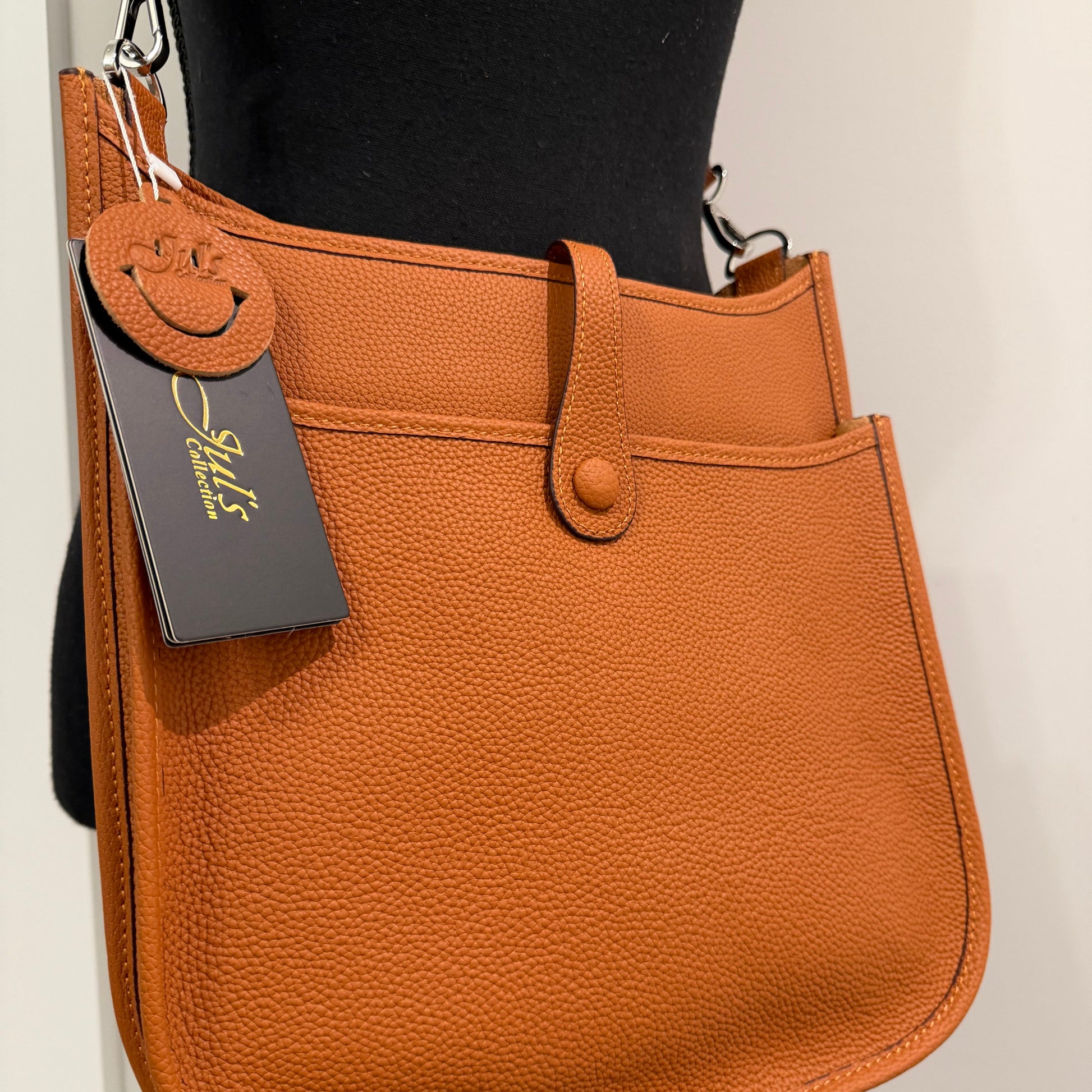 Brown leather saddle pad with a visible brand tag on a neutral background