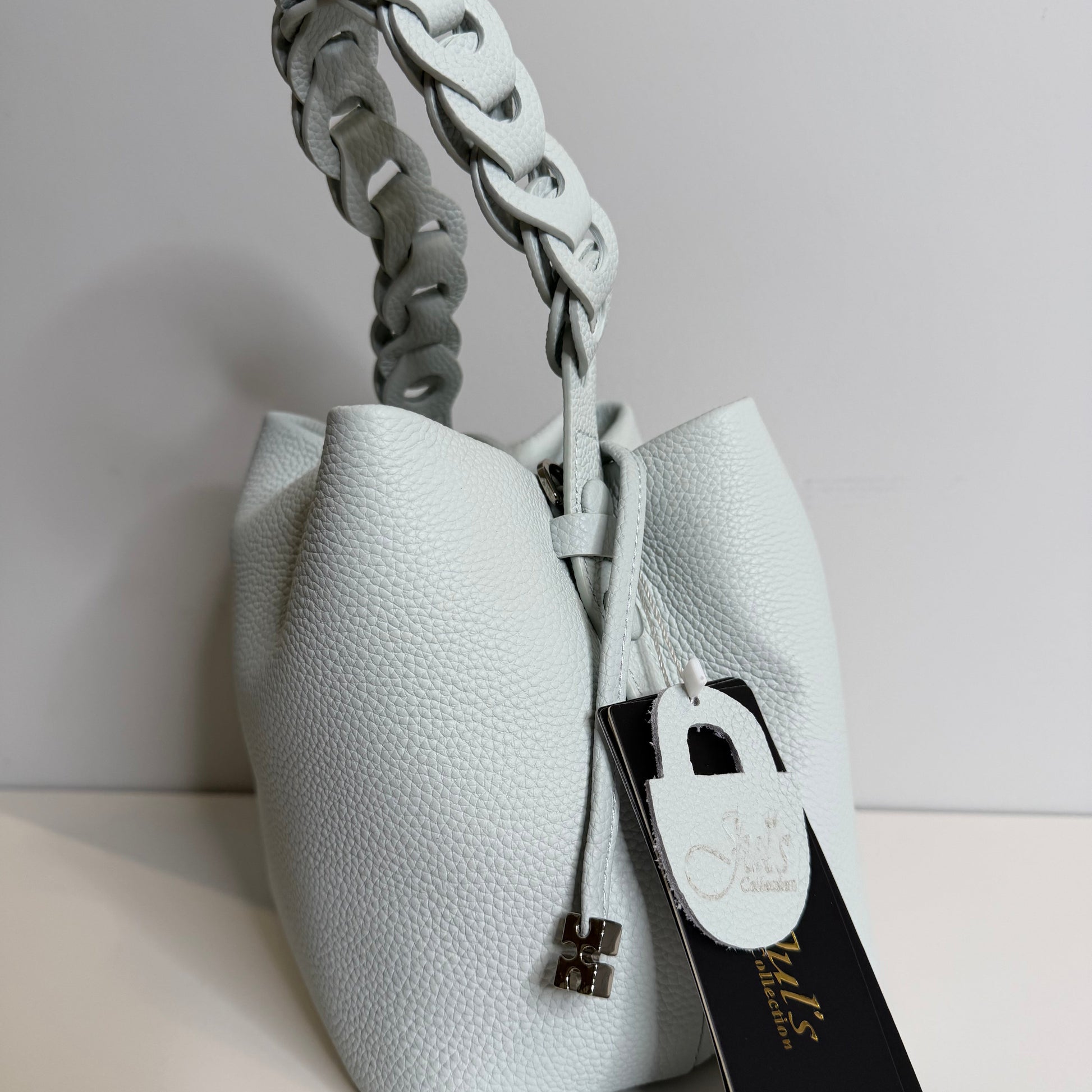 White leather handbag with braided handle on a light gray background