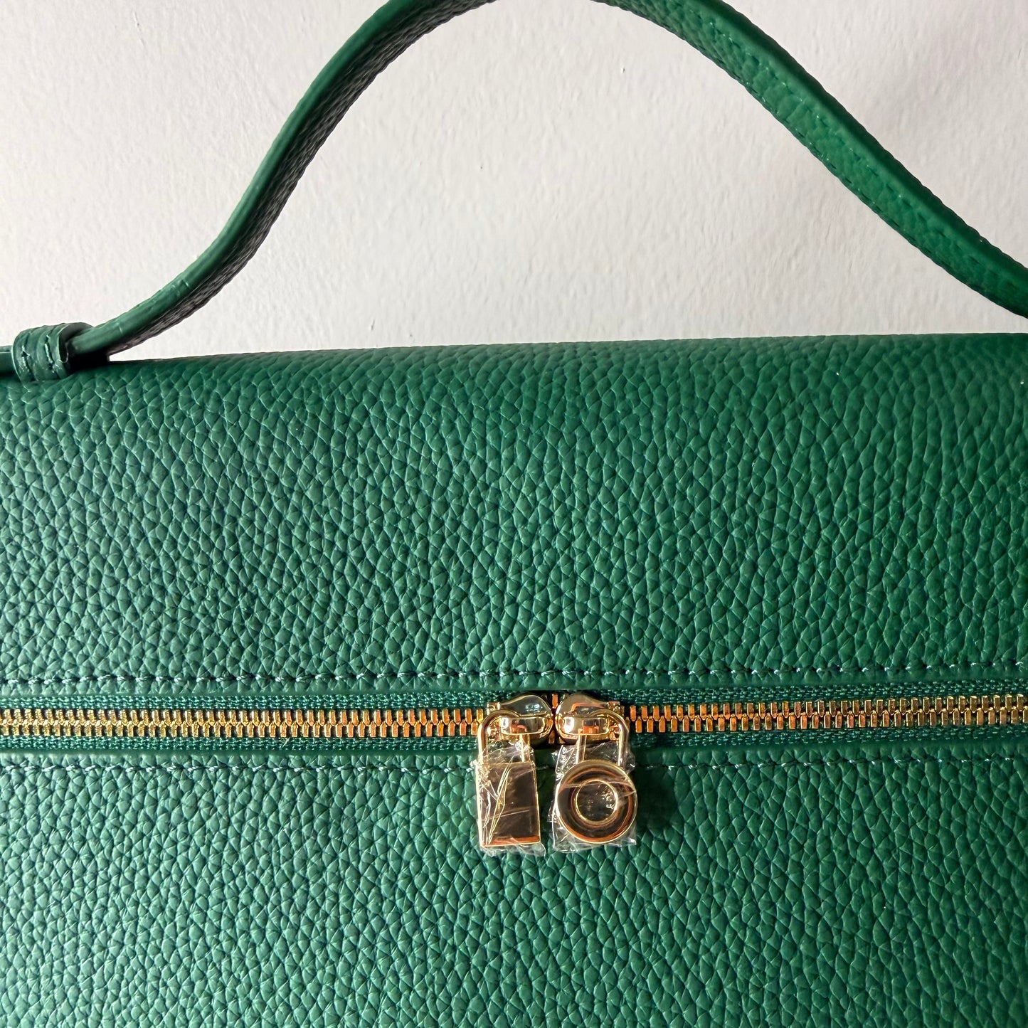 Close-up of a green leather bag with a gold zipper.