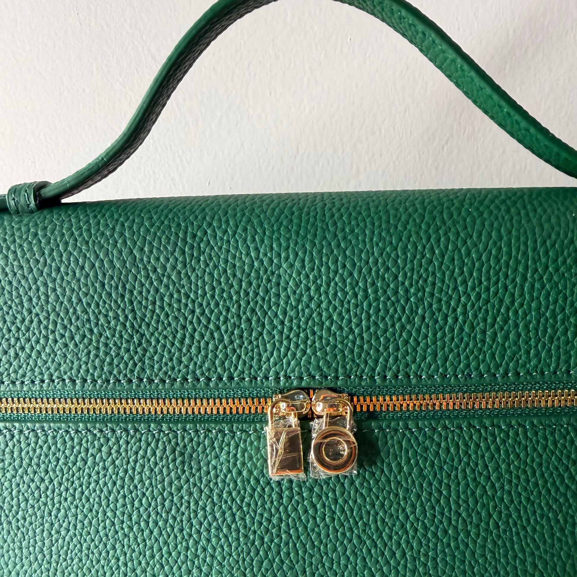 Close-up of a green leather bag with a gold zipper.