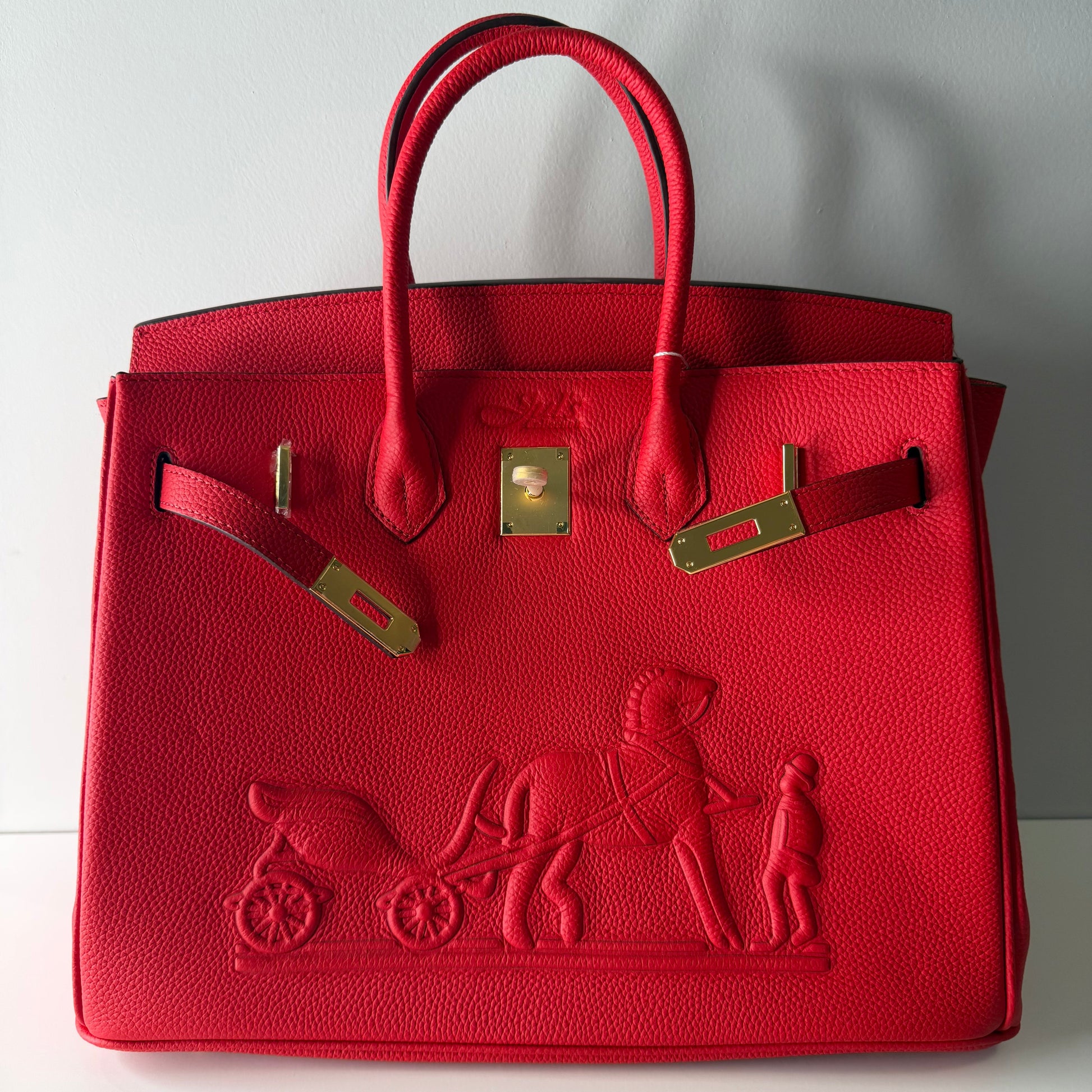 Red handbag with gold accents on a light gray background