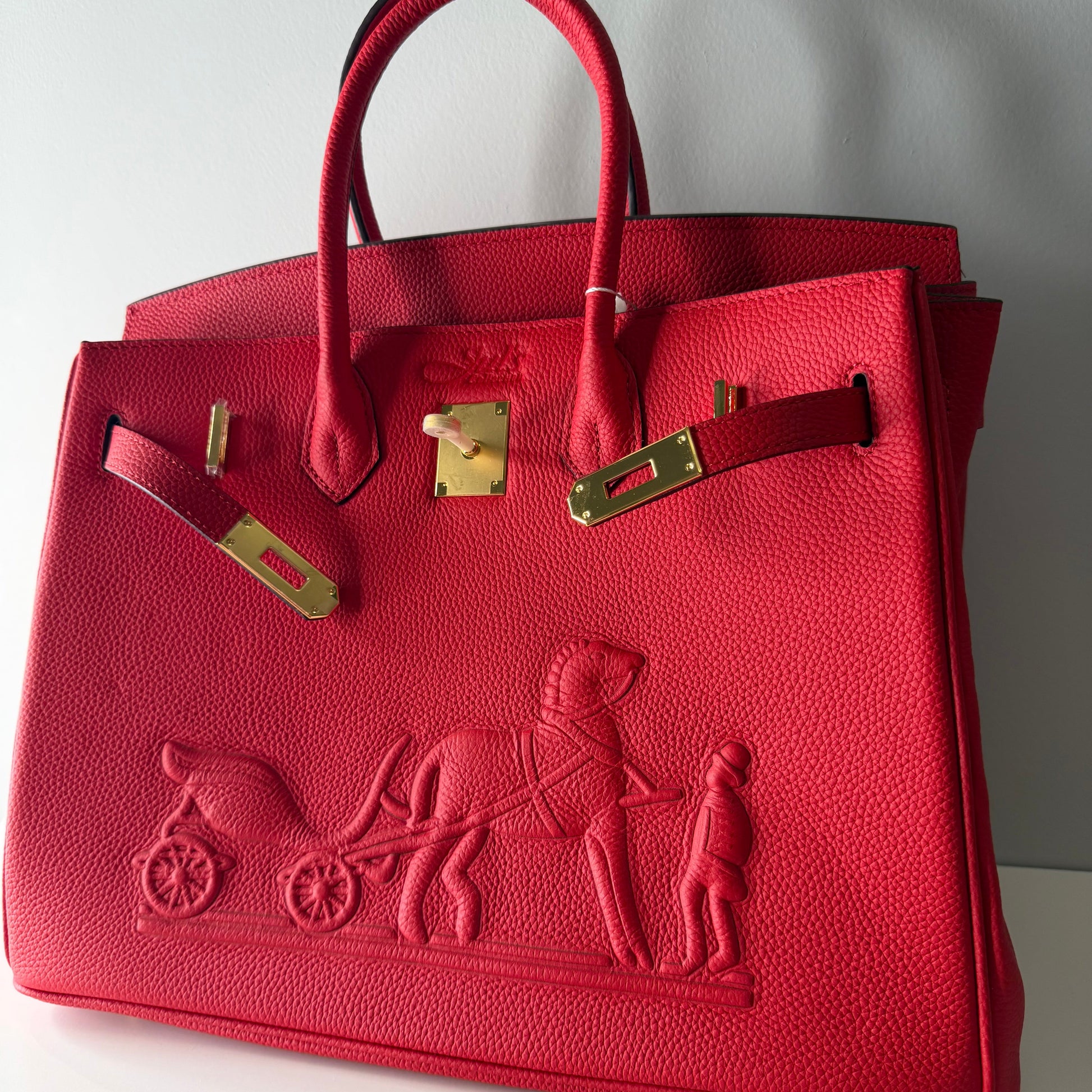 Red handbag with gold hardware on a light gray background
