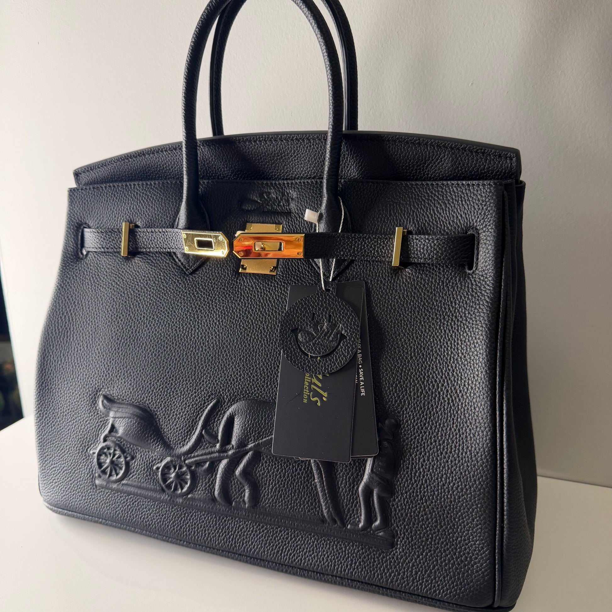 Black leather handbag with gold accents on a light gray background