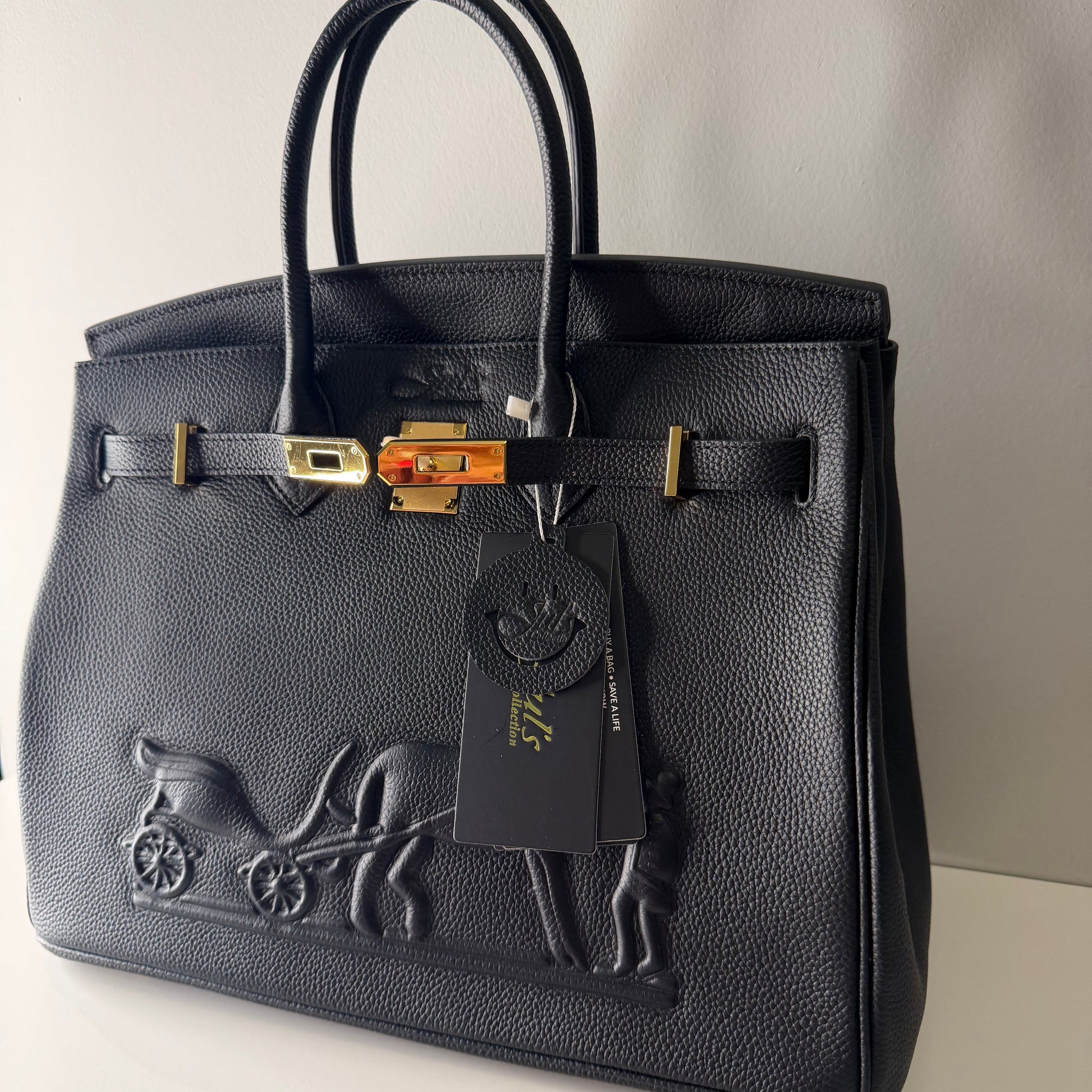 Black leather handbag with gold accents on a light gray background