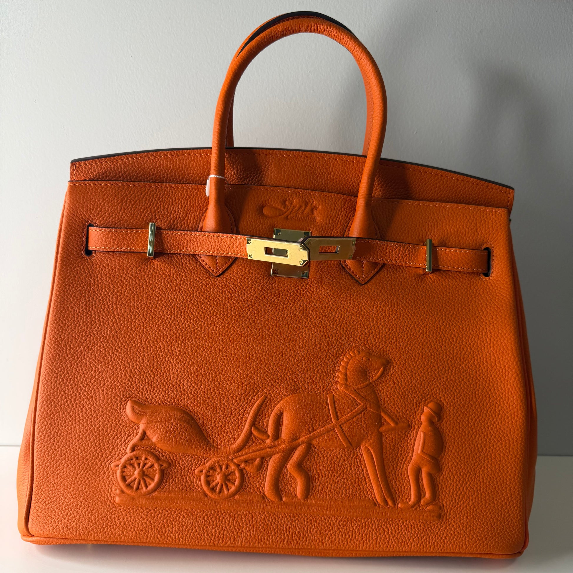 Brown leather handbag with embossed design on a light gray surface