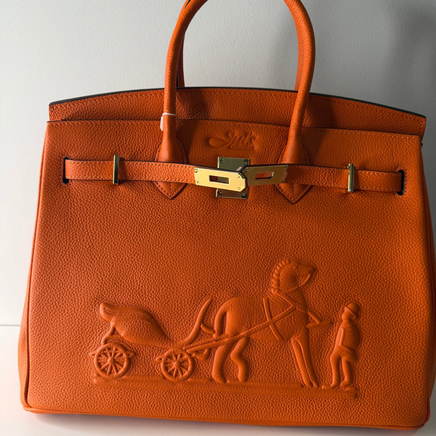 Brown leather handbag with embossed design on a white background