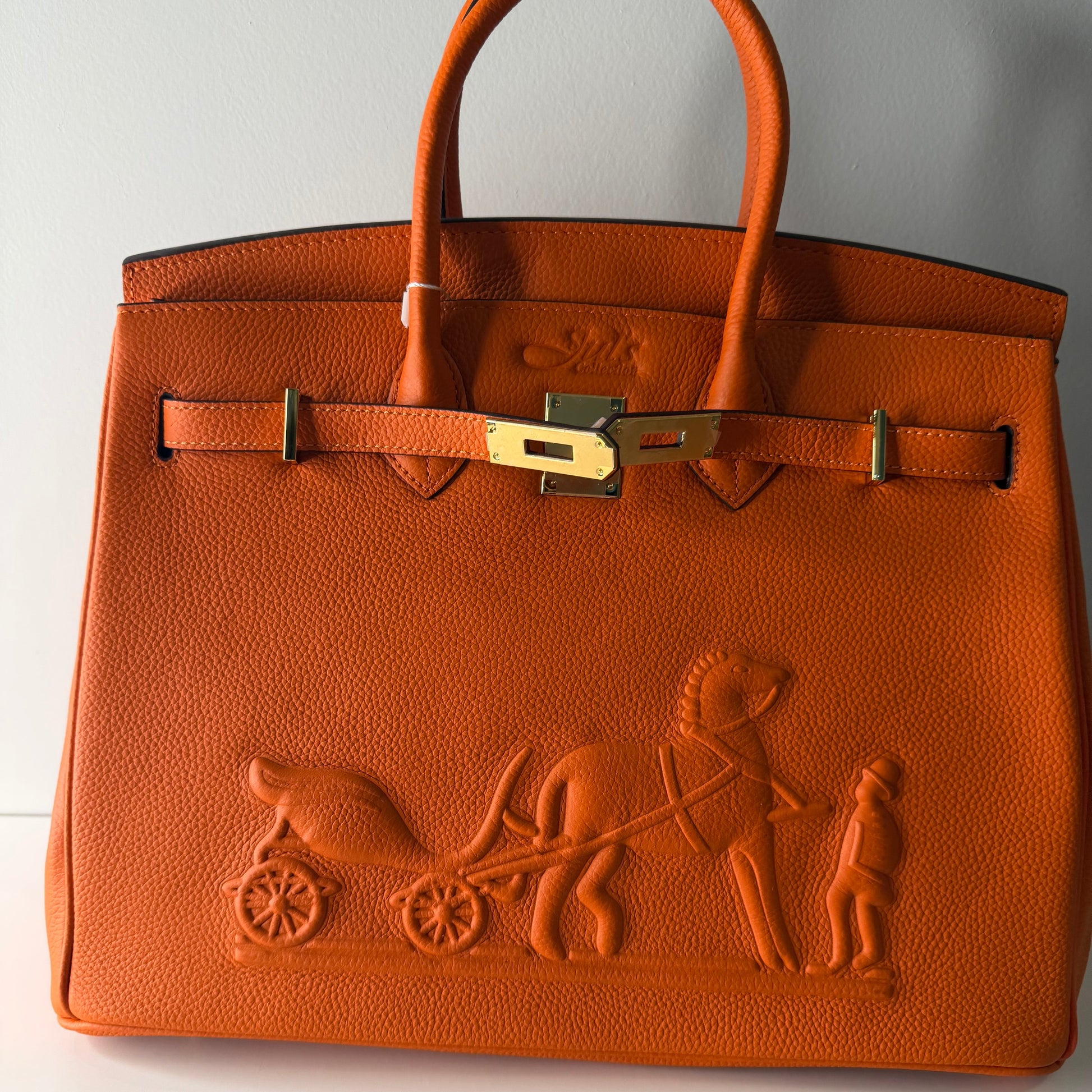 Brown leather handbag with embossed design on a white background