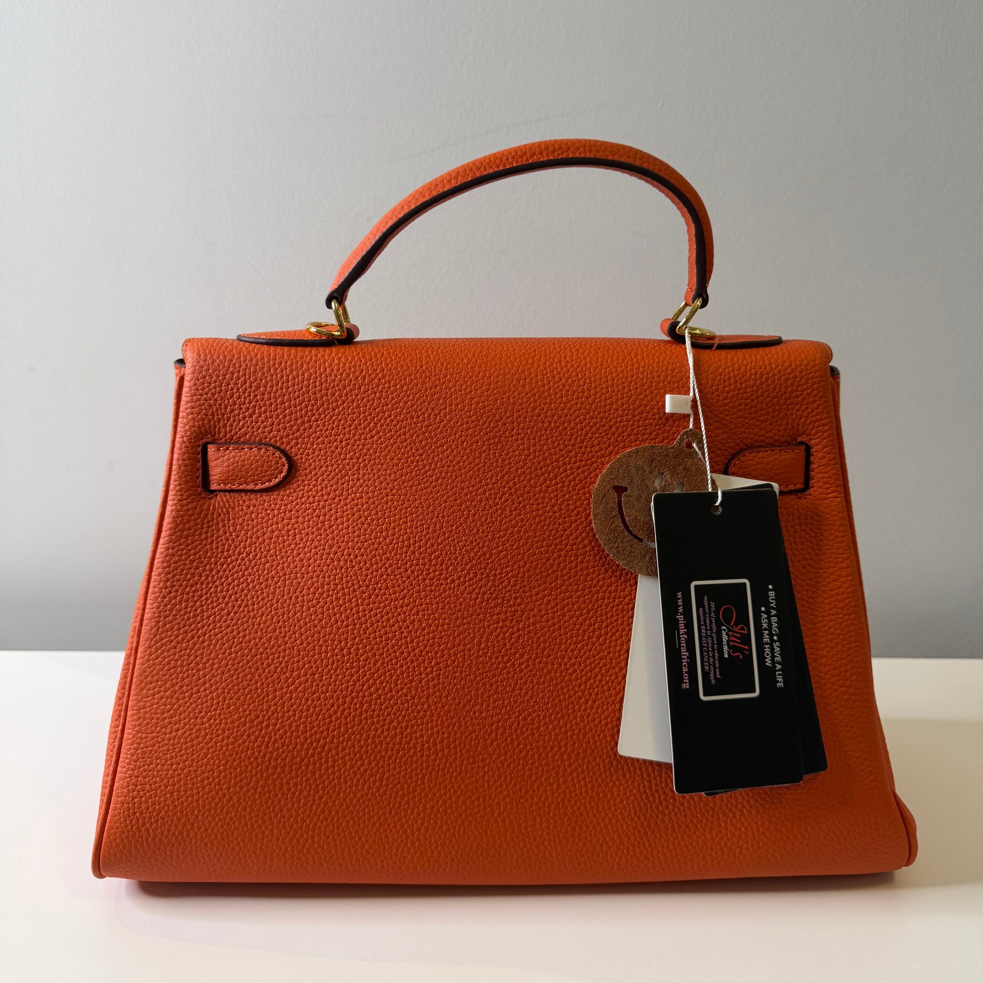 Brown leather handbag with a tag on a light gray background