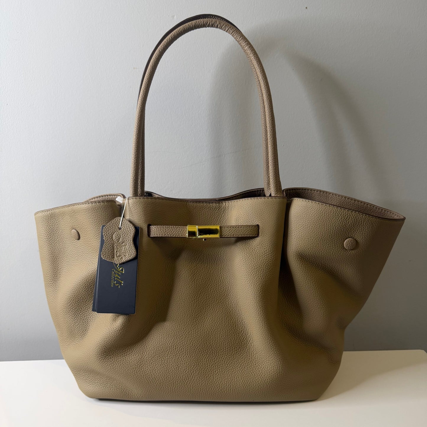 Beige handbag with a visible brand tag on a white background