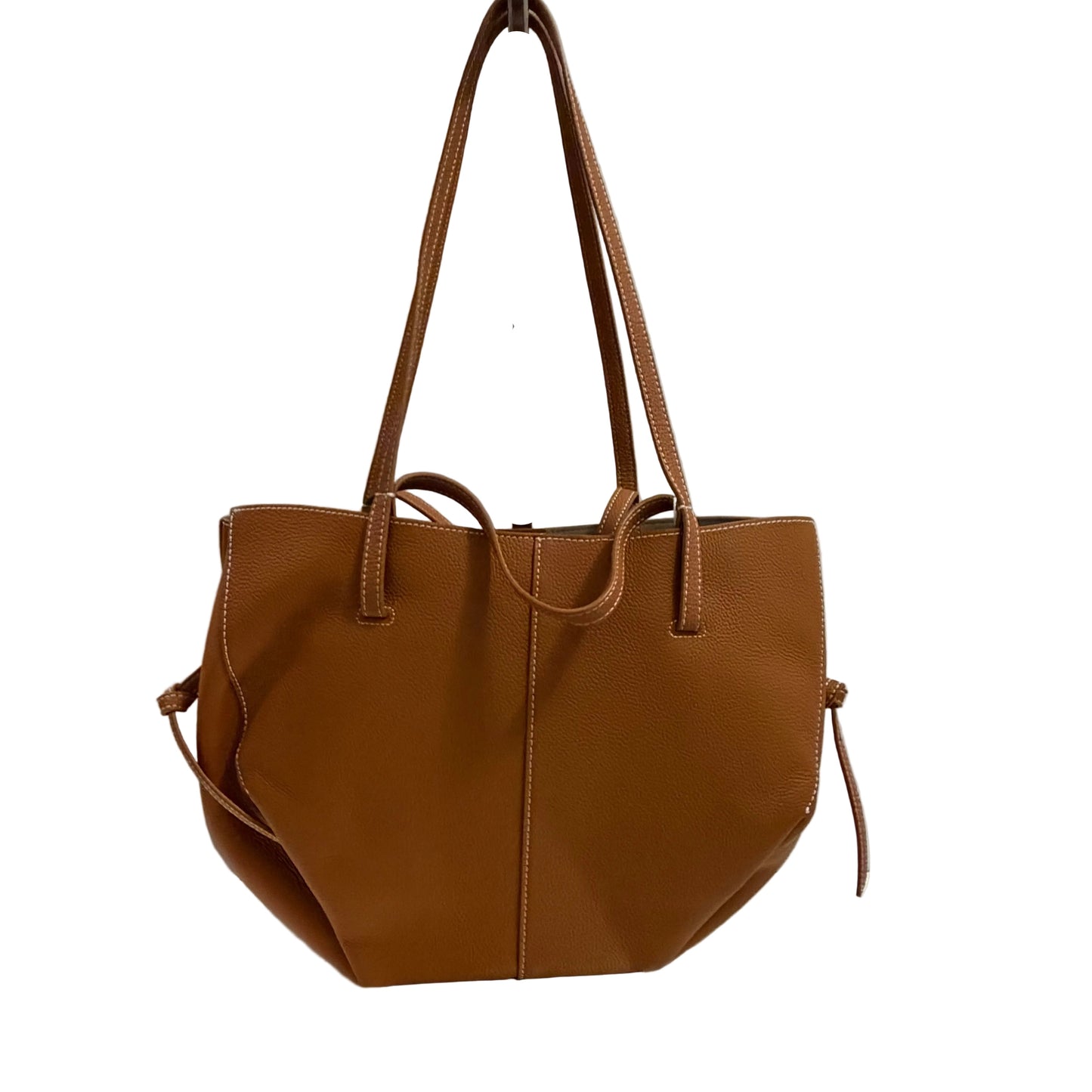 Brown leather handbag on a white surface with a gray background