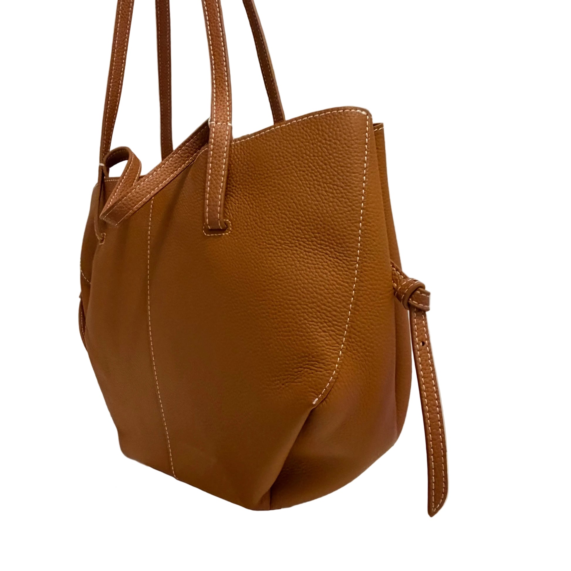 Brown leather handbag on a reflective surface with a neutral background