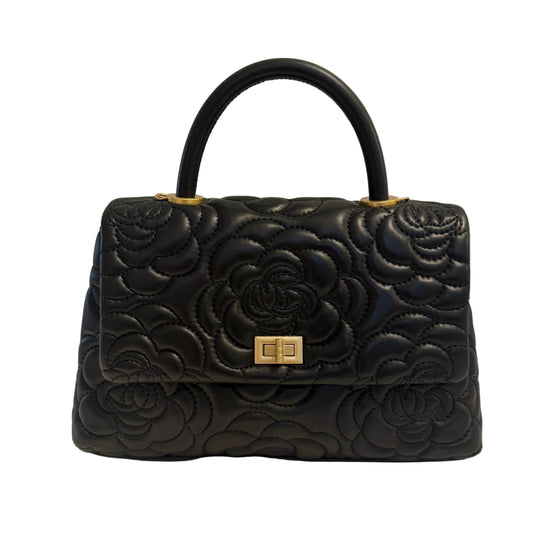 Black quilted handbag with floral design on a light background