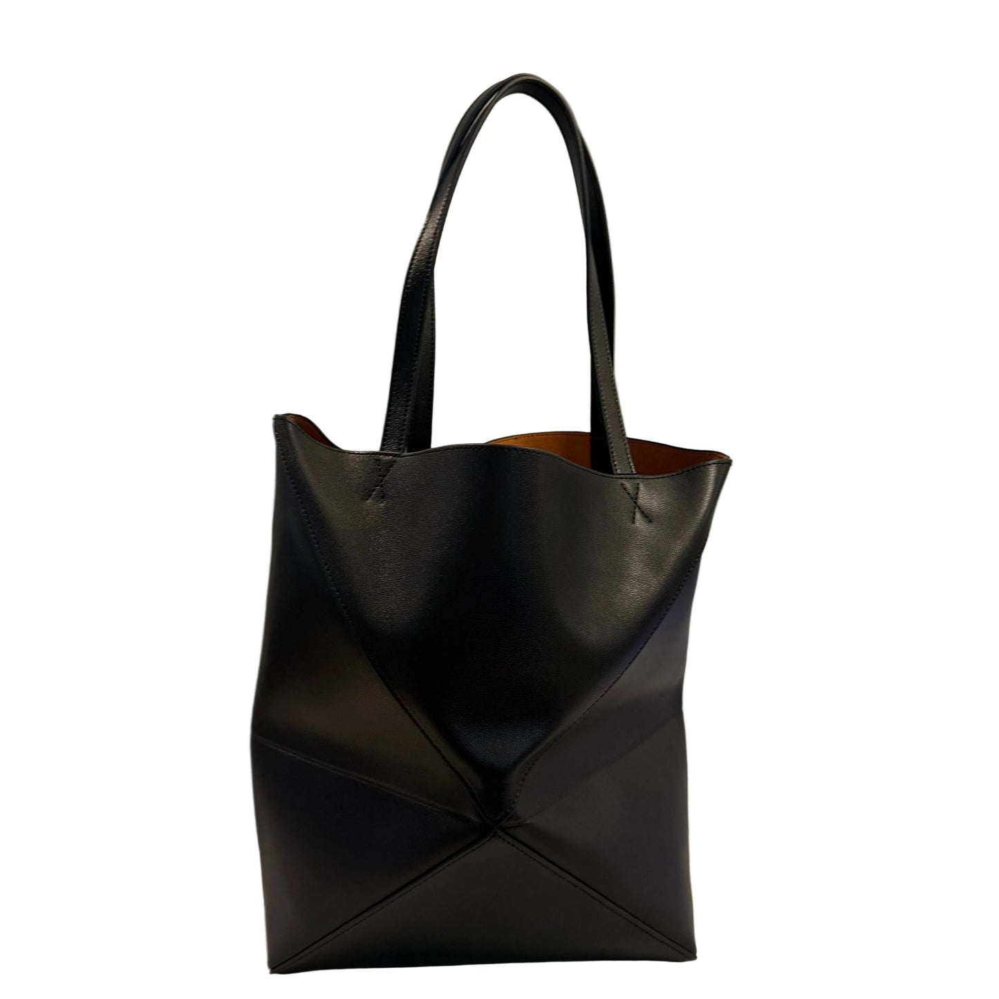 Black leather tote bag on a light surface with a gray background