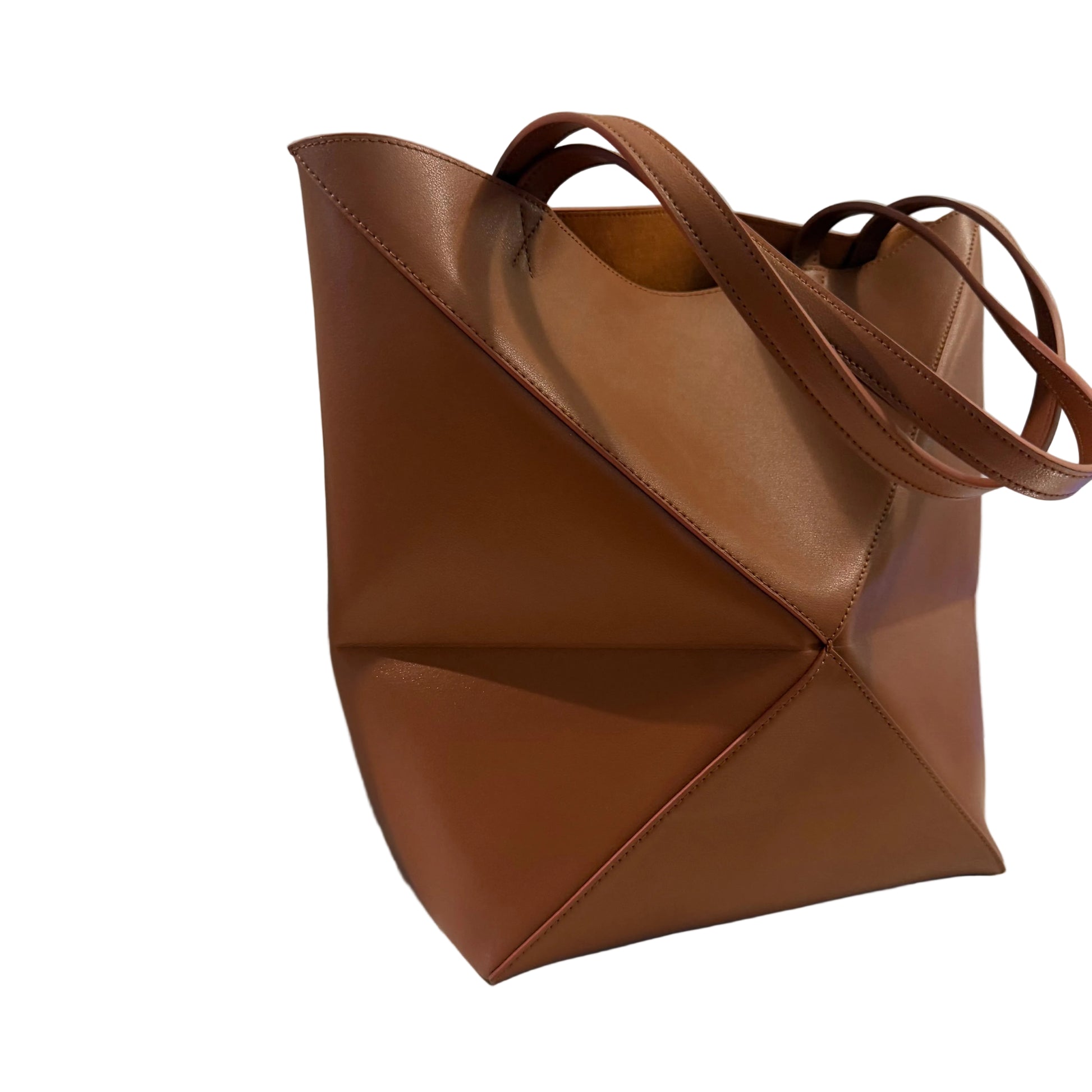 Brown leather tote bag on a light surface with a neutral background