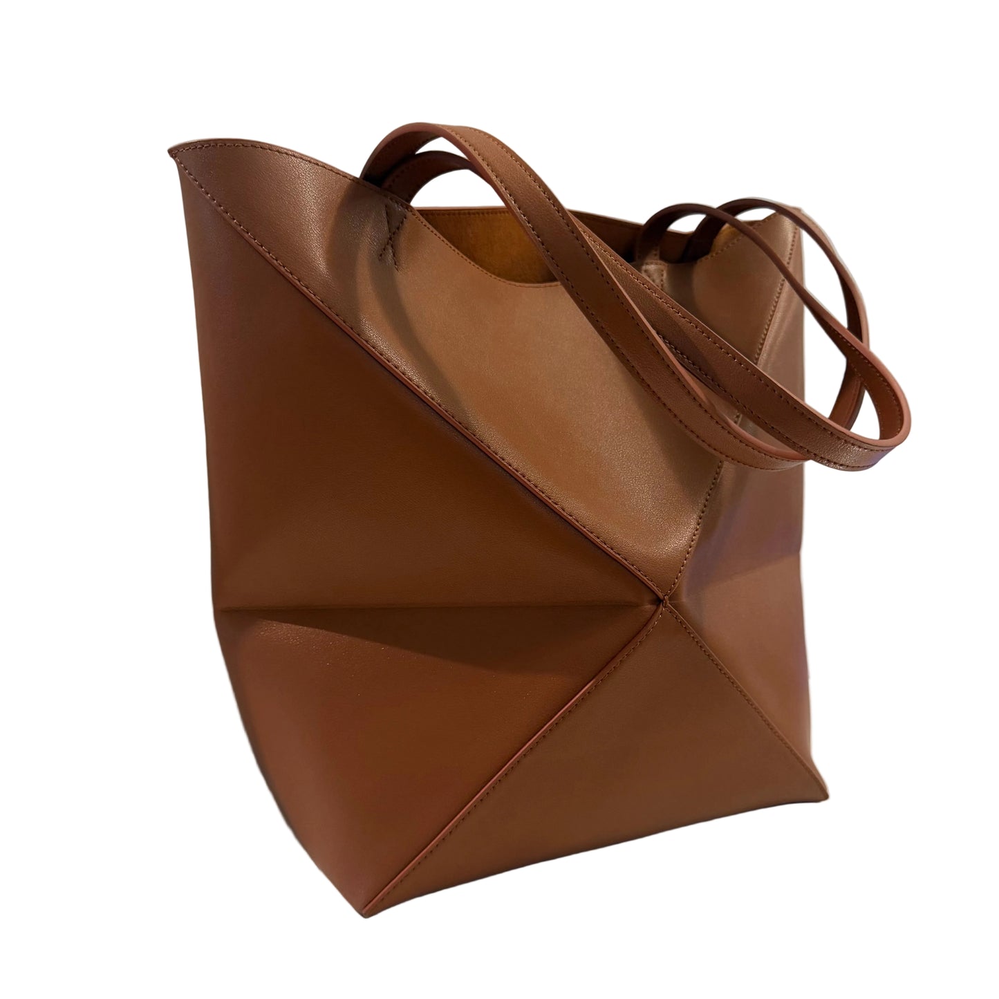 Brown leather tote bag on a light surface with a neutral background
