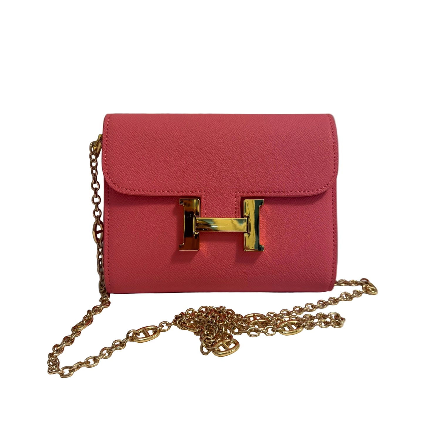 Pink handbag with gold chain and clasp on a white surface with gray background