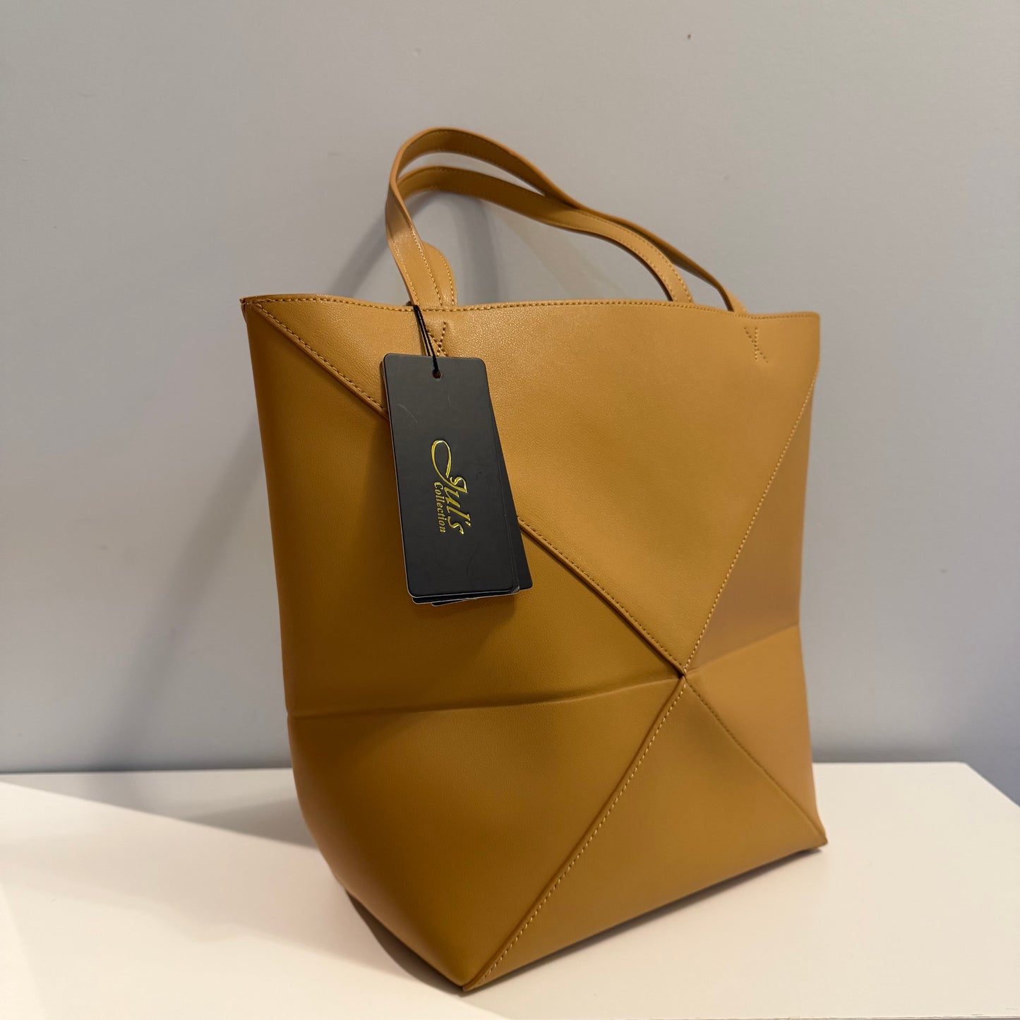 Brown leather tote bag with a tag on a light gray background